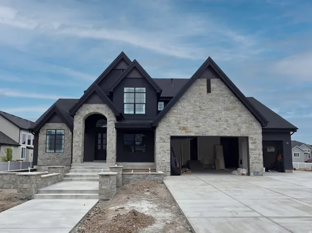 View of front of property with stone siding, concrete driveway, and an attached garage