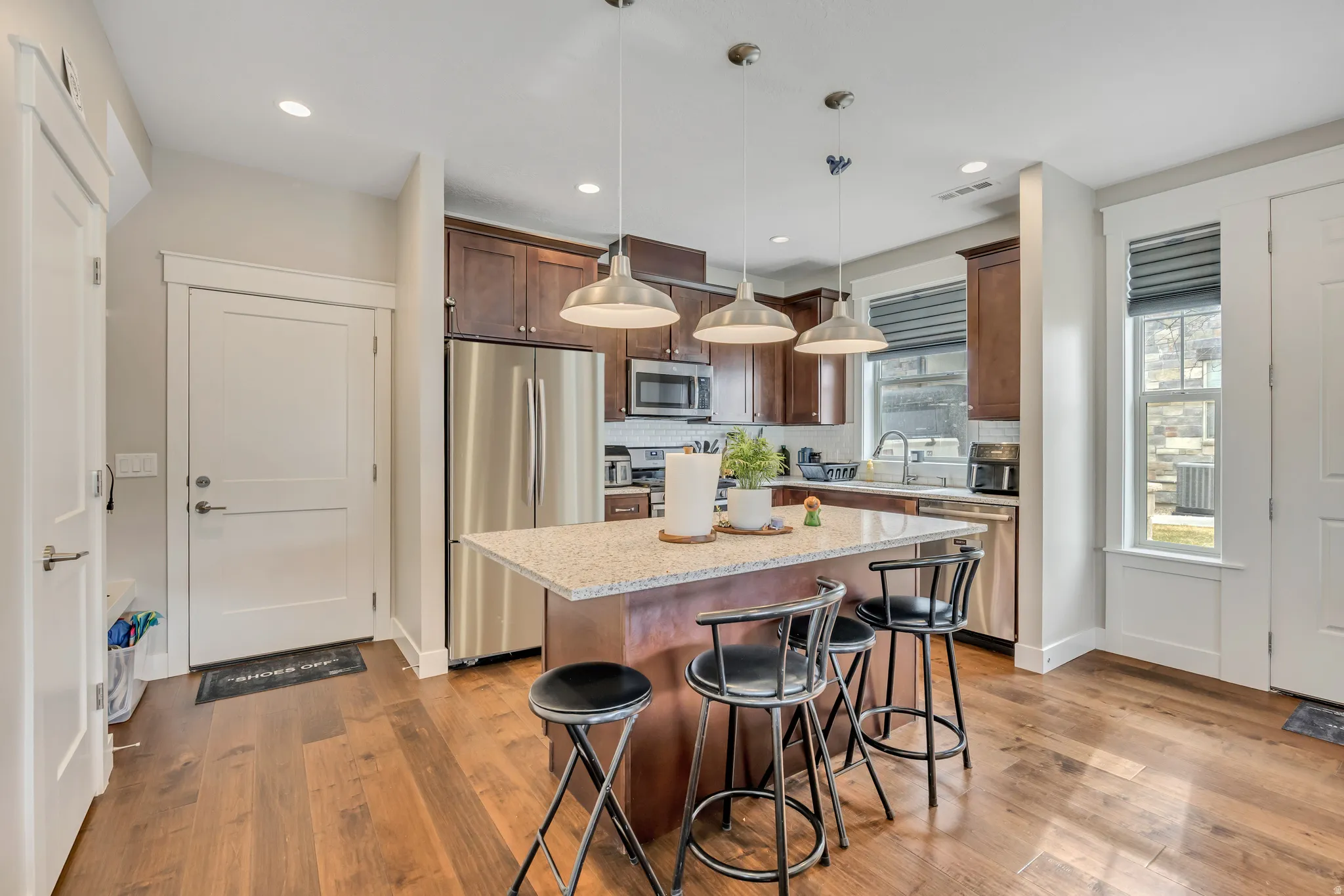 Kitchen featuring hanging light fixtures, stainless steel appliances, light stone counters, a kitchen island, and a kitchen breakfast bar