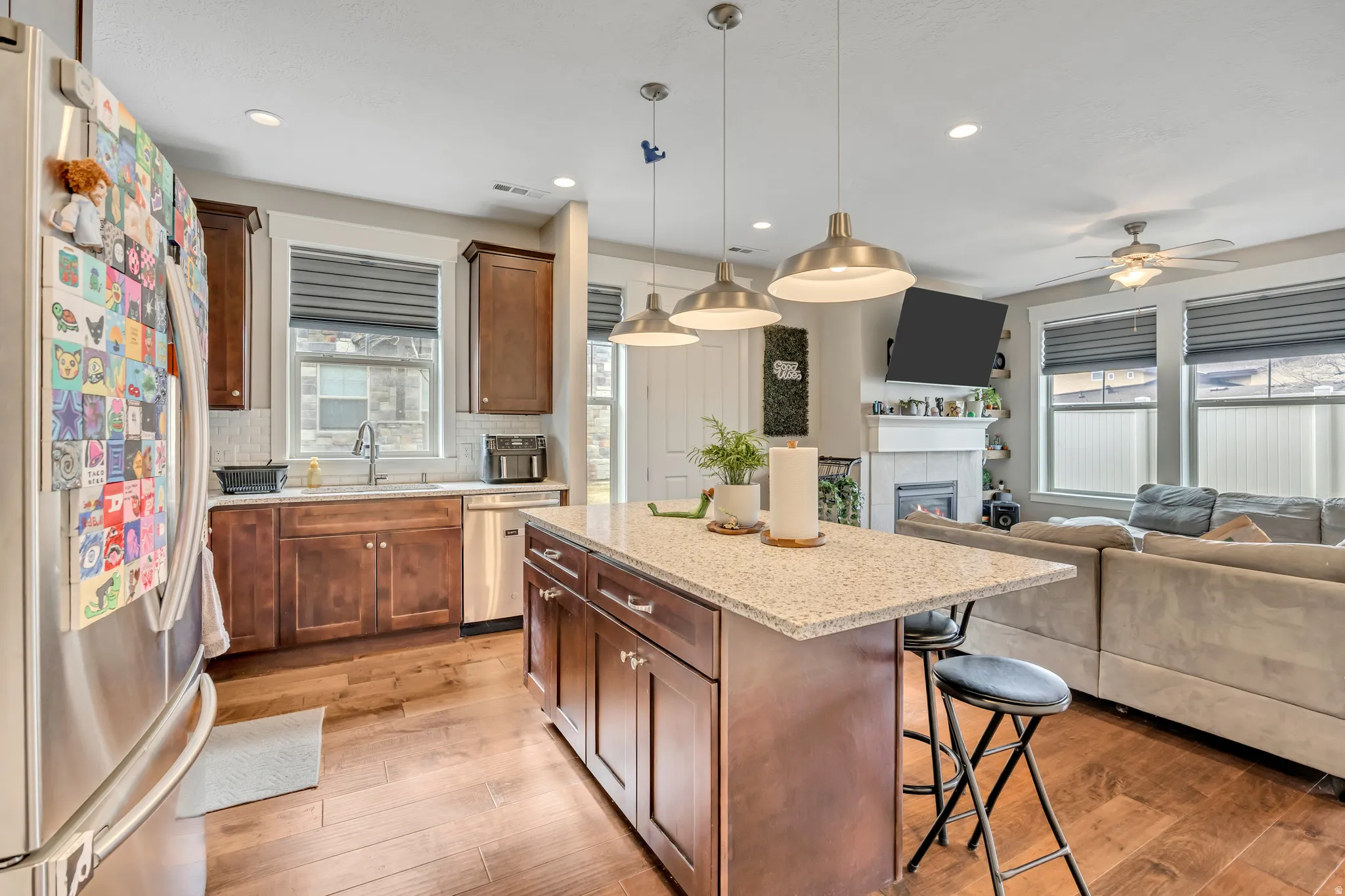 Kitchen with a kitchen breakfast bar, stainless steel appliances, light stone counters, hanging light fixtures, and a center island
