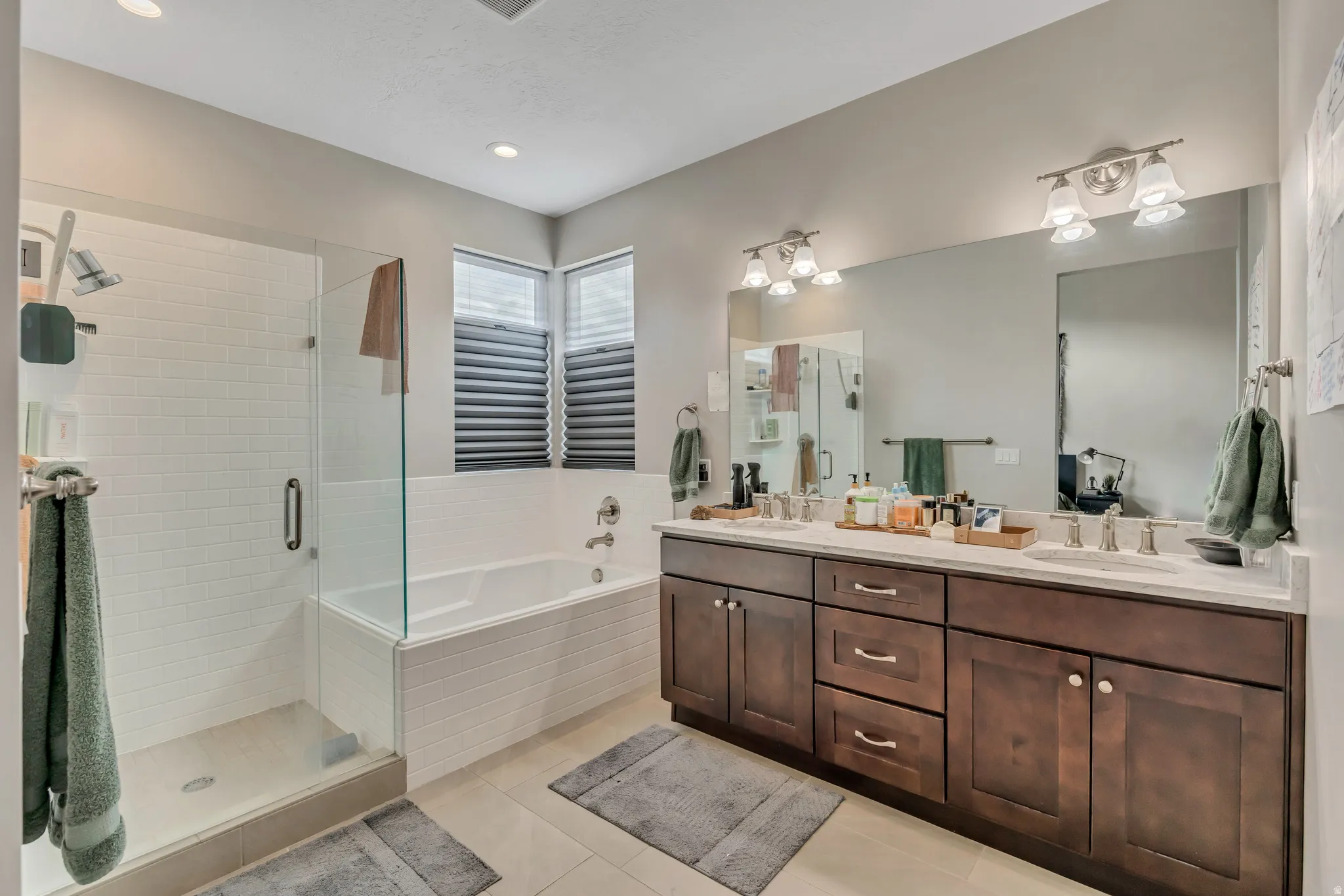 Full bath featuring a shower stall, double vanity, a bath, light tile patterned flooring, and recessed lighting
