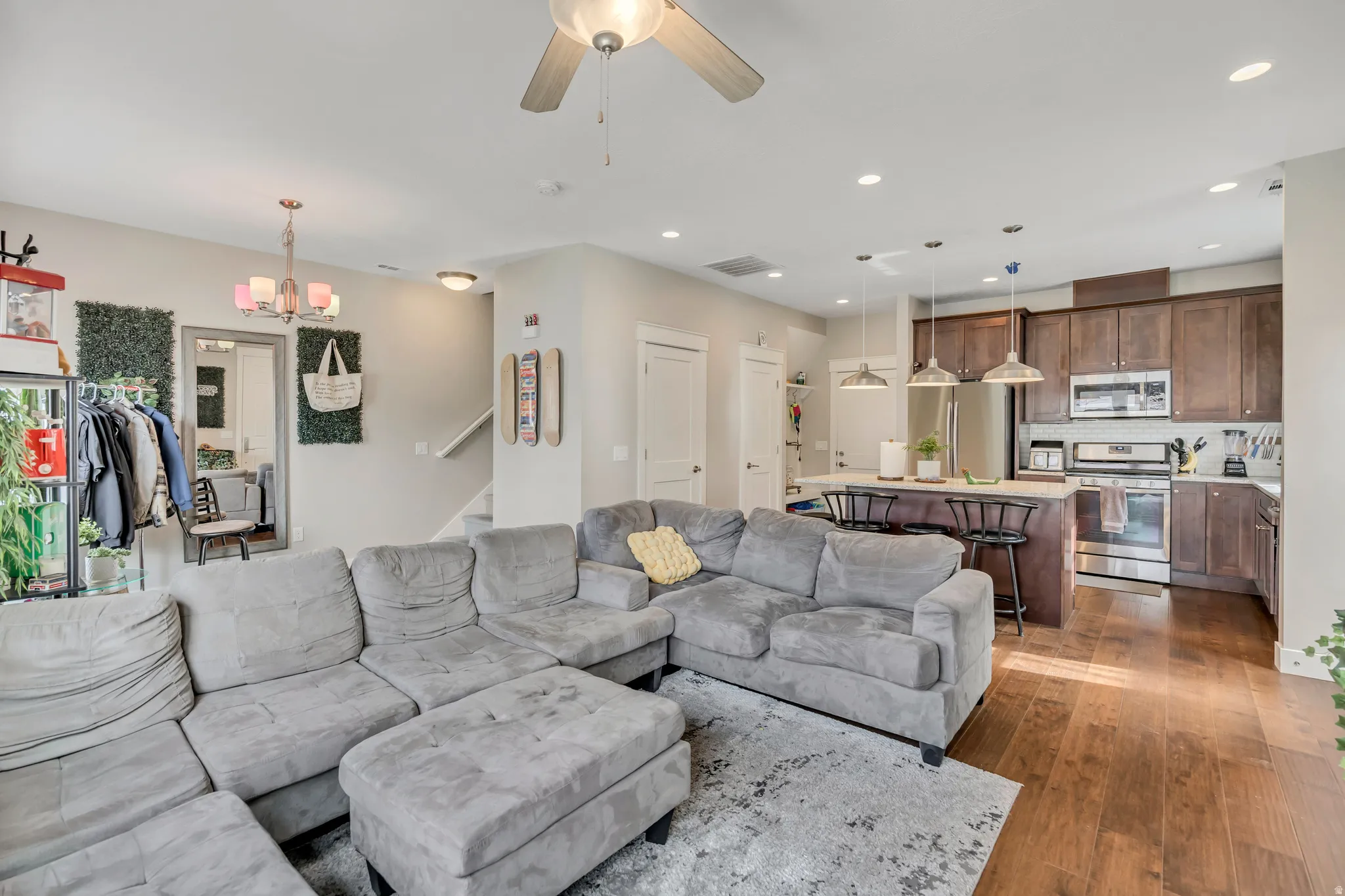 Living area featuring ceiling fan, dark wood-style flooring, and a chandelier