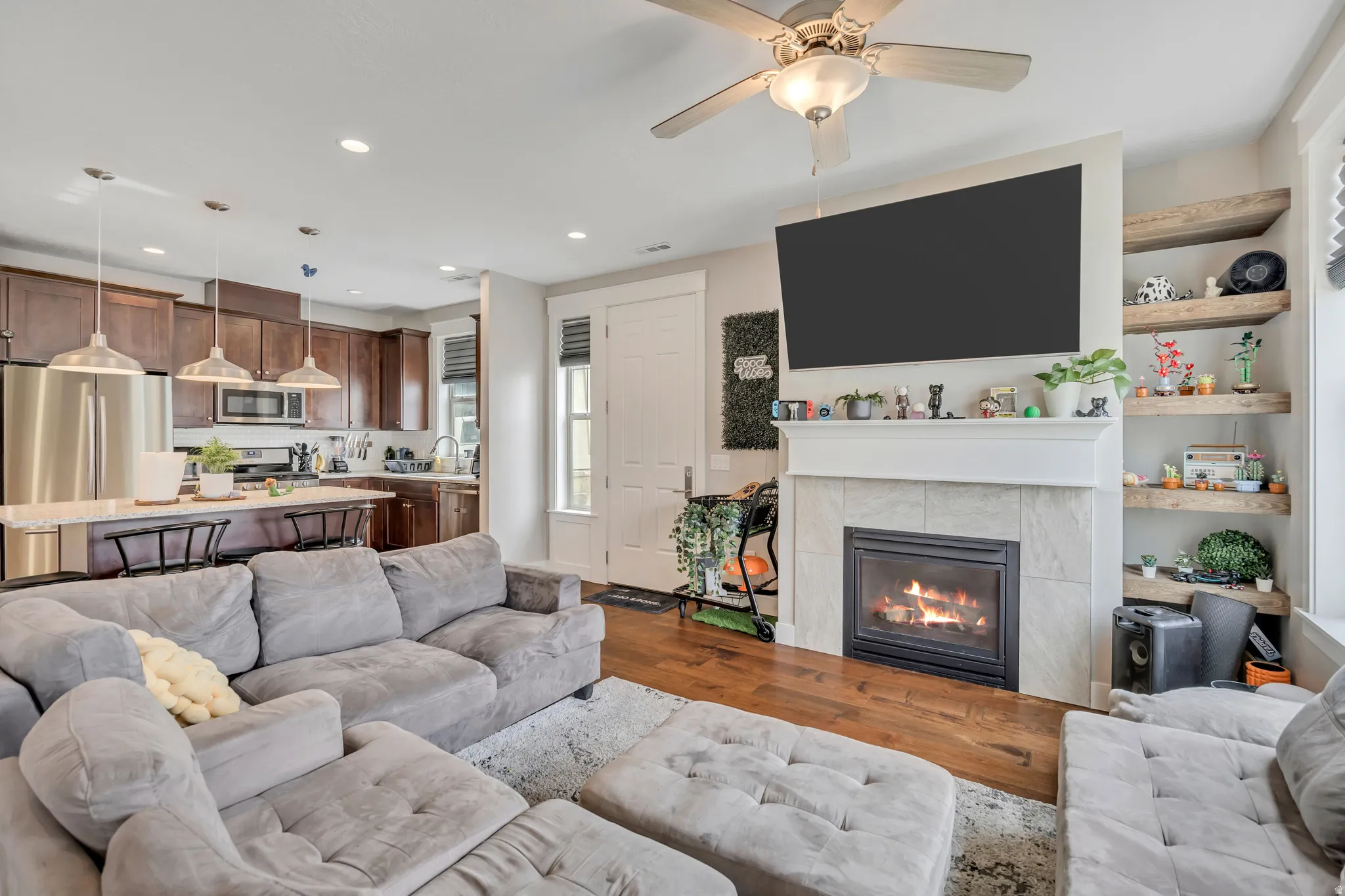 Living room featuring wood finished floors, a tiled fireplace, recessed lighting, and a ceiling fan