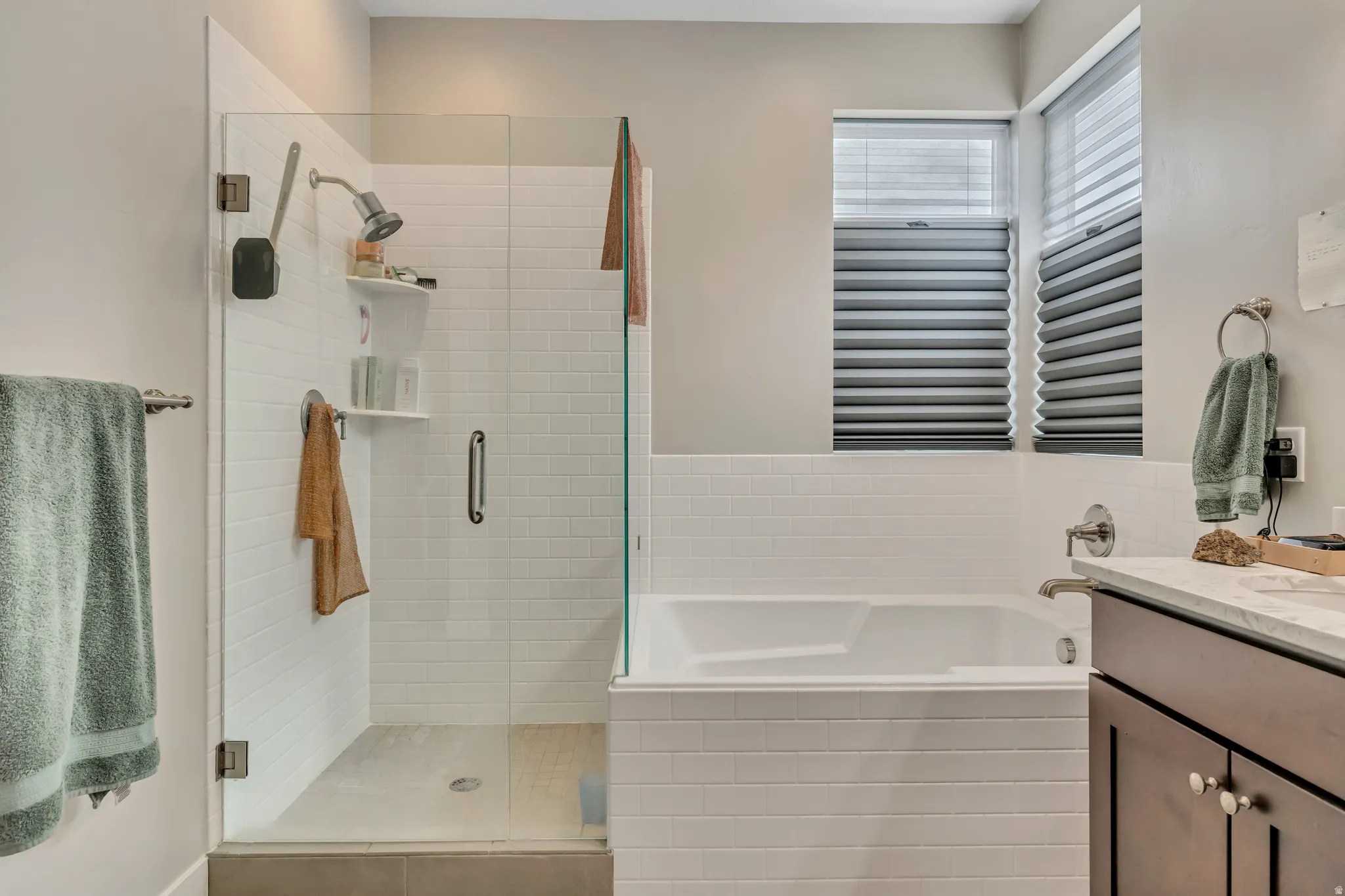 Bathroom with vanity, a bath, and a stall shower