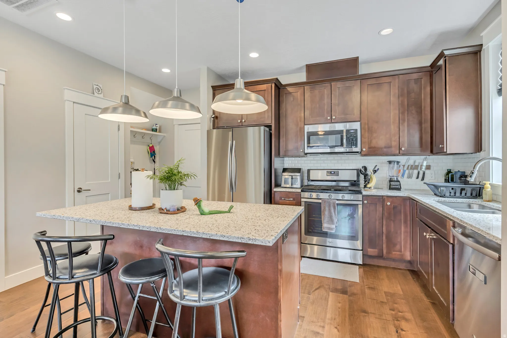 Kitchen with stainless steel appliances, light stone countertops, a breakfast bar, pendant lighting, and a center island