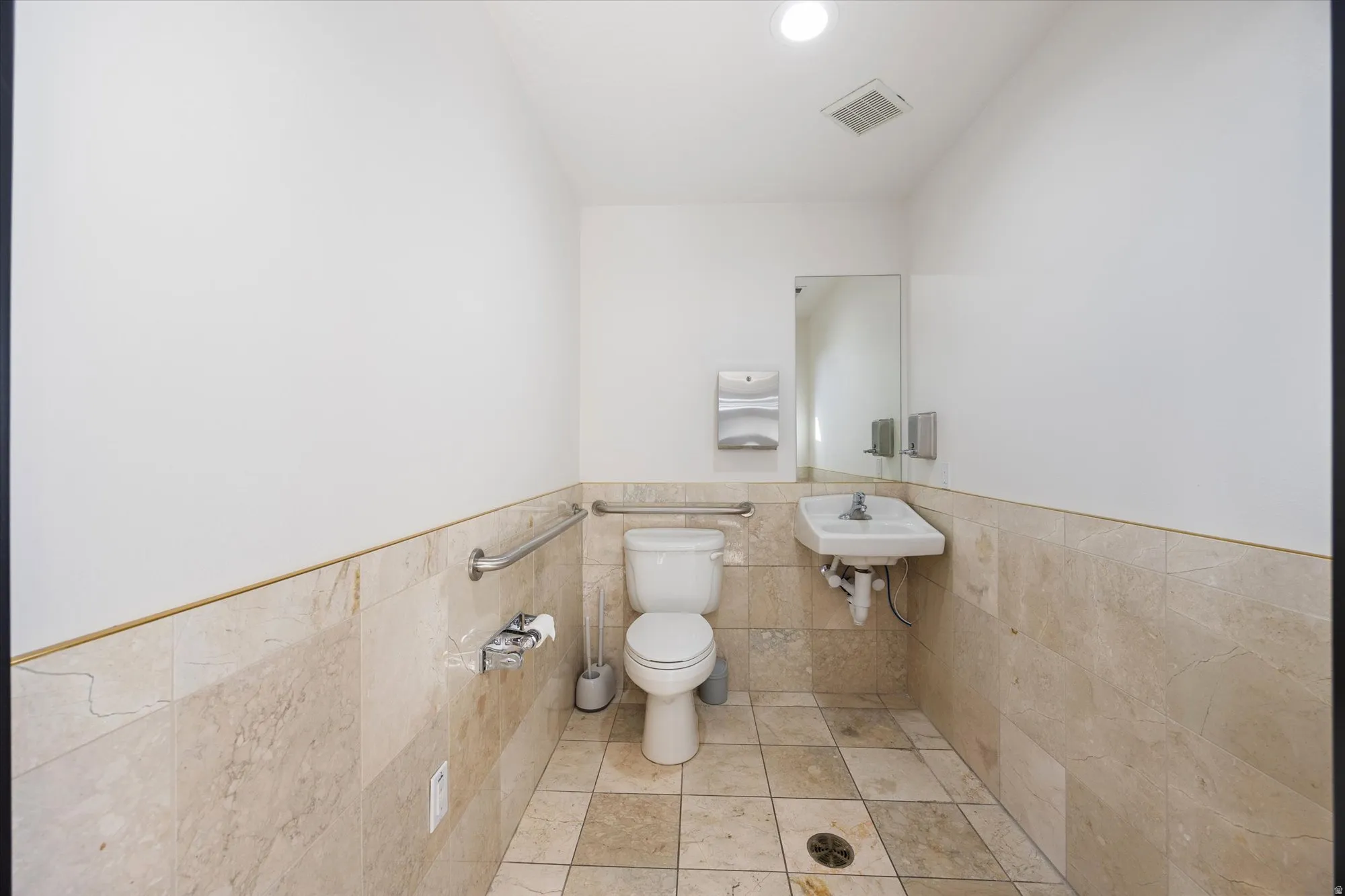 Half bathroom with tile walls, wainscoting, and recessed lighting