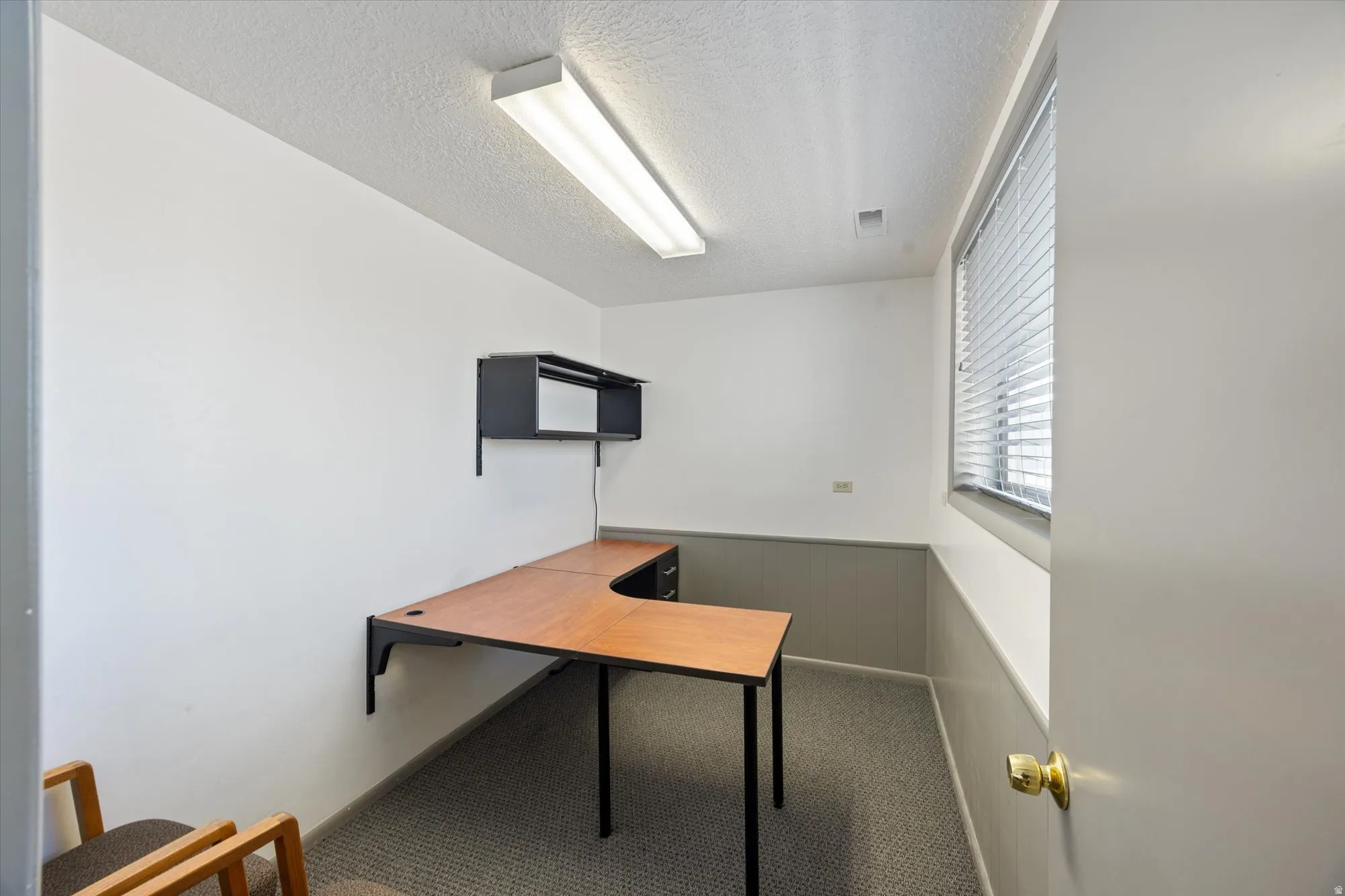 Unfurnished office featuring a wainscoted wall and a textured ceiling