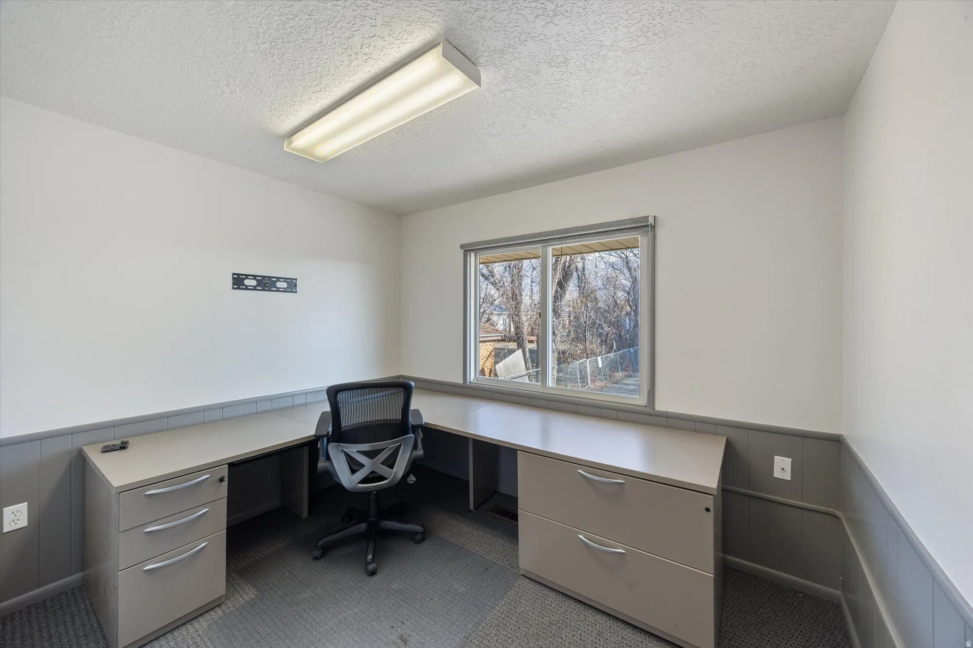 Office with a wainscoted wall, a textured ceiling, and built in study area