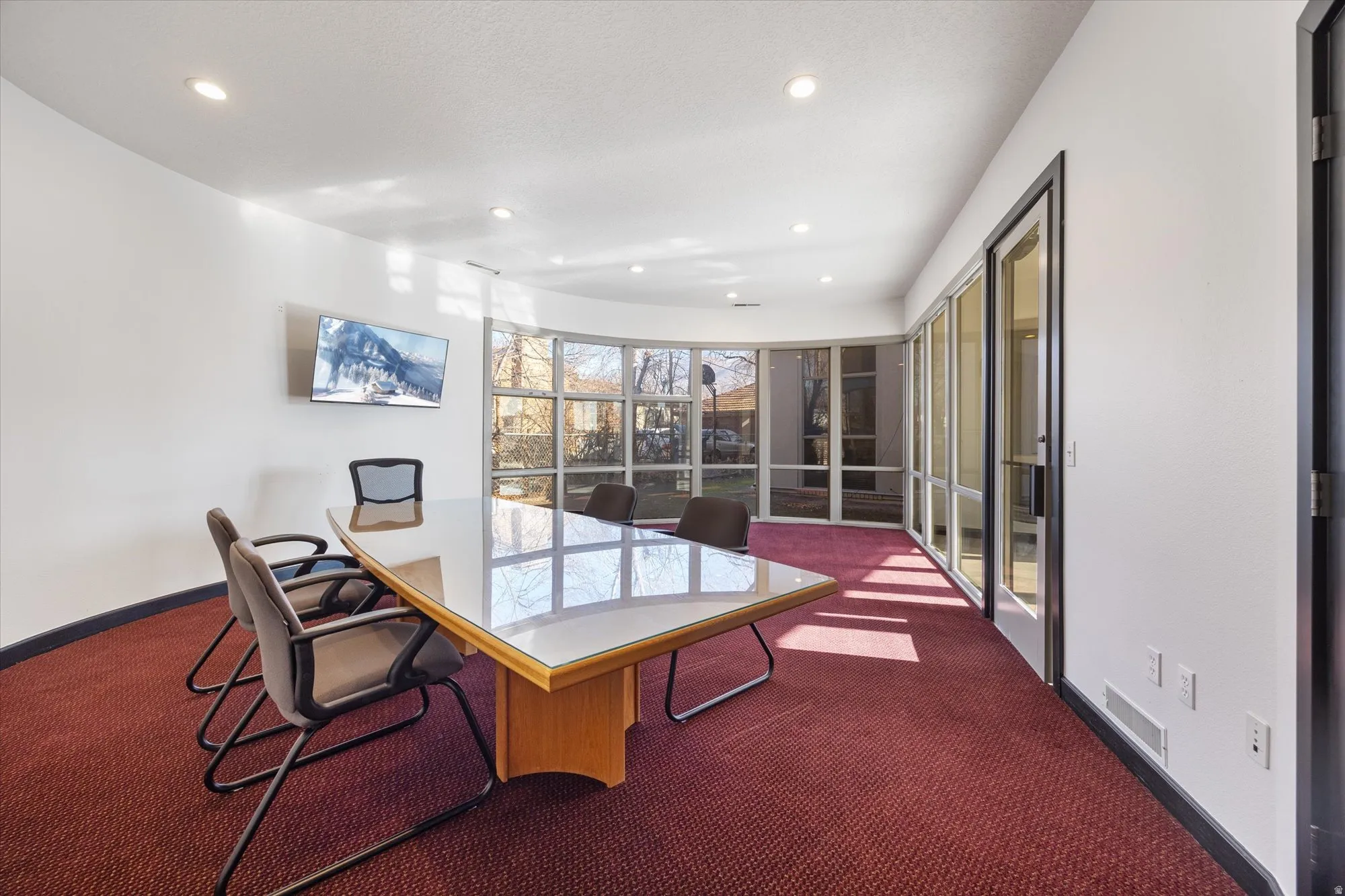 Home office with dark colored carpet and recessed lighting