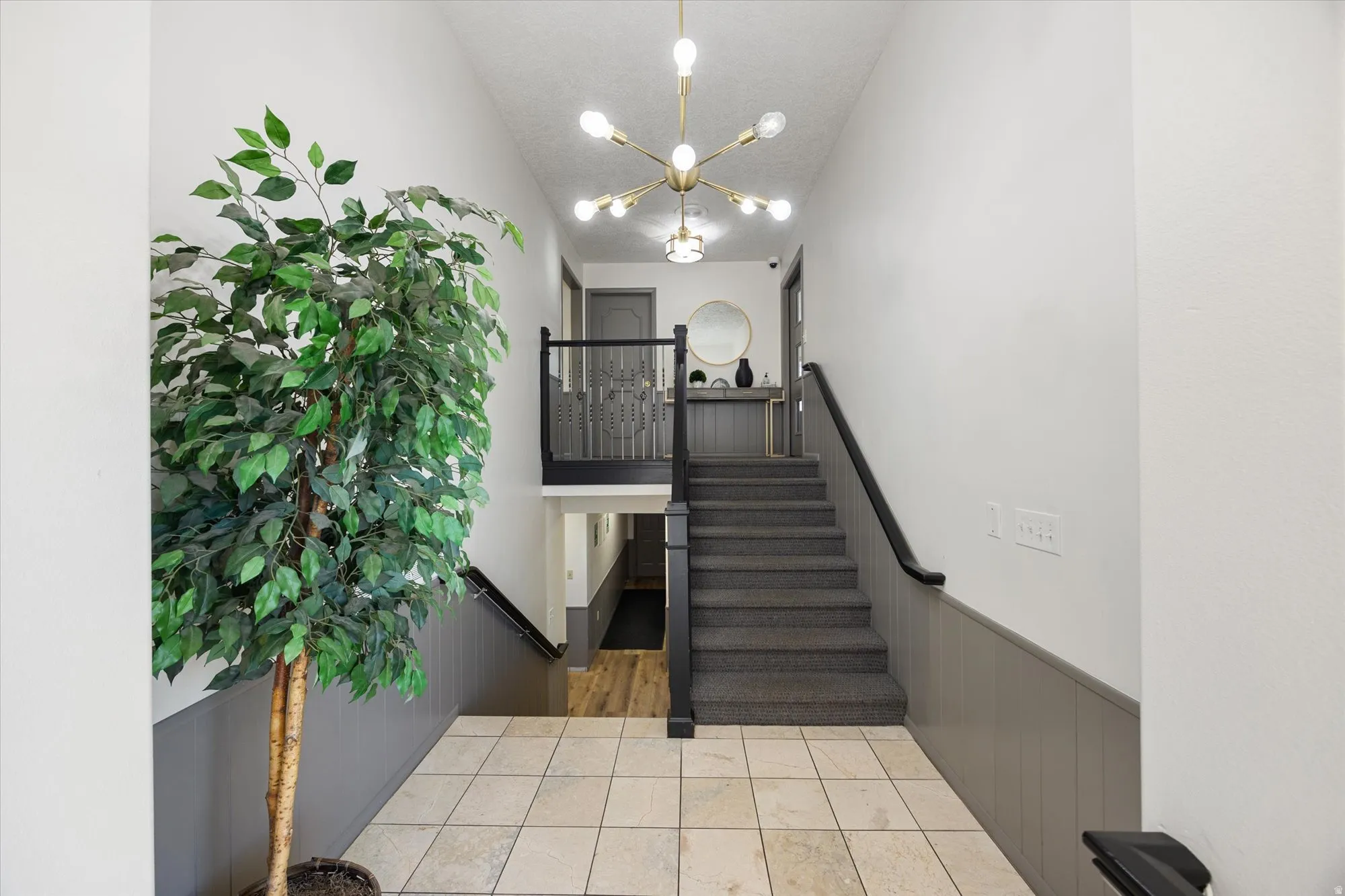 Staircase with a wainscoted wall and a chandelier