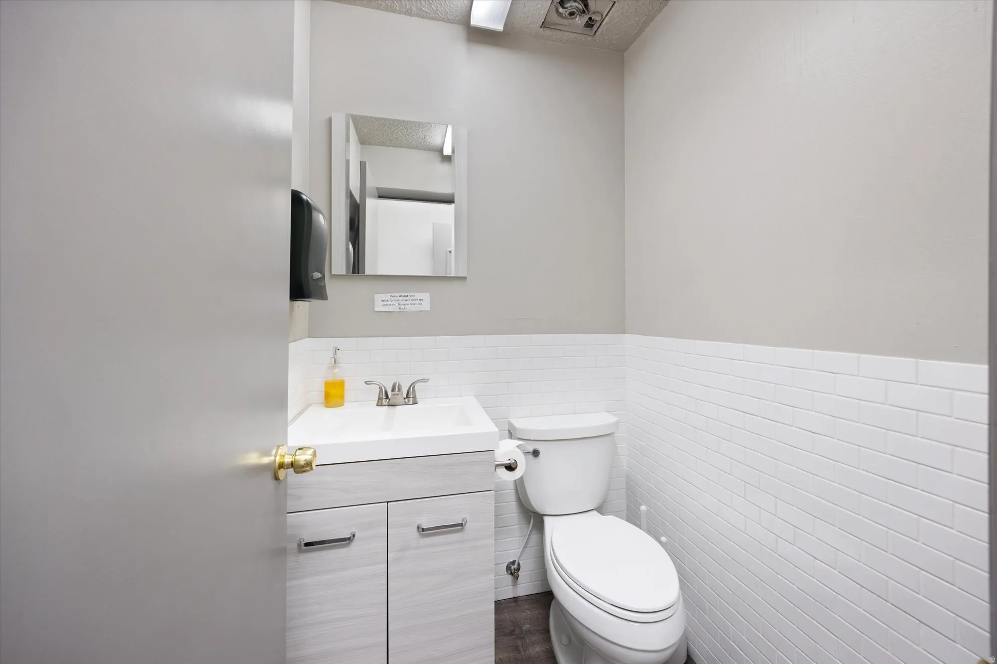 Bathroom featuring vanity, wainscoting, tile walls, and a textured ceiling