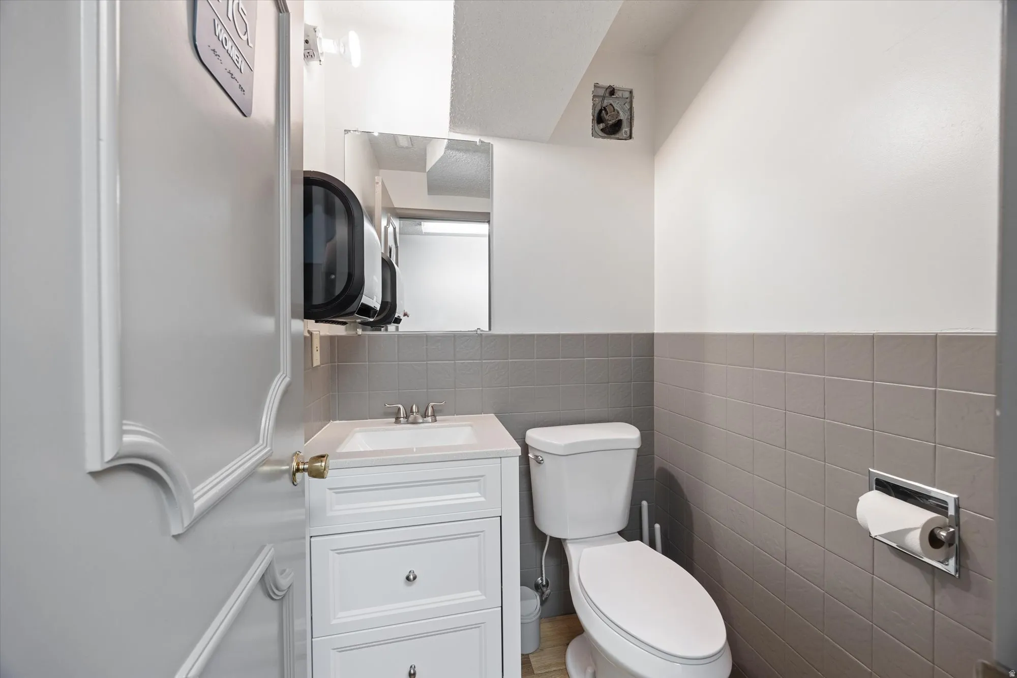 Bathroom with vanity, tile walls, and a wainscoted wall