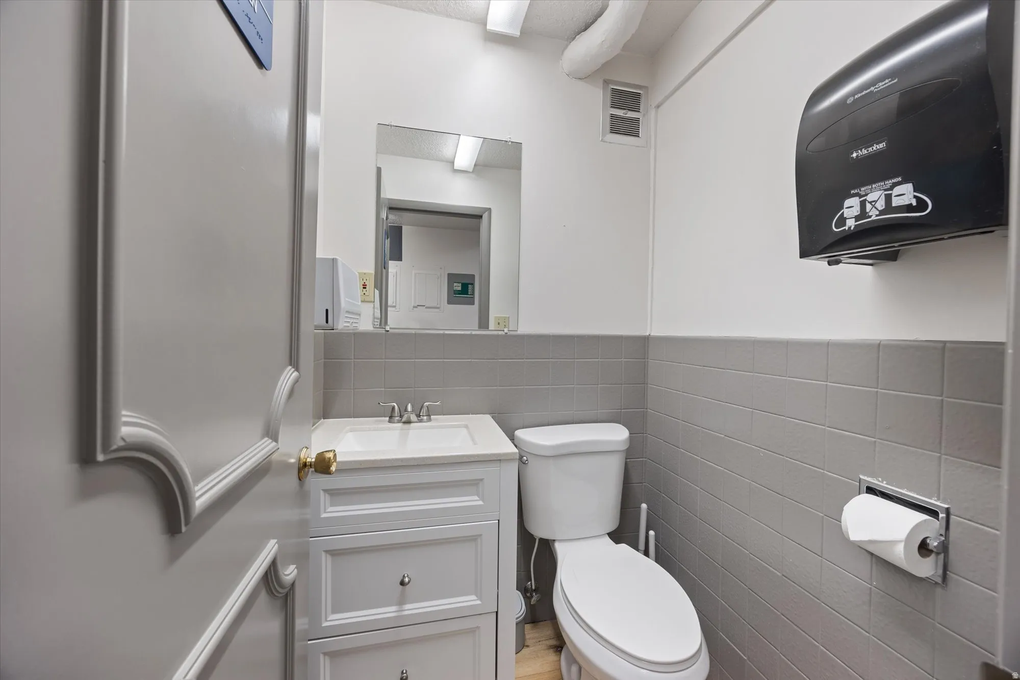 Half bathroom featuring vanity, tile walls, and wainscoting