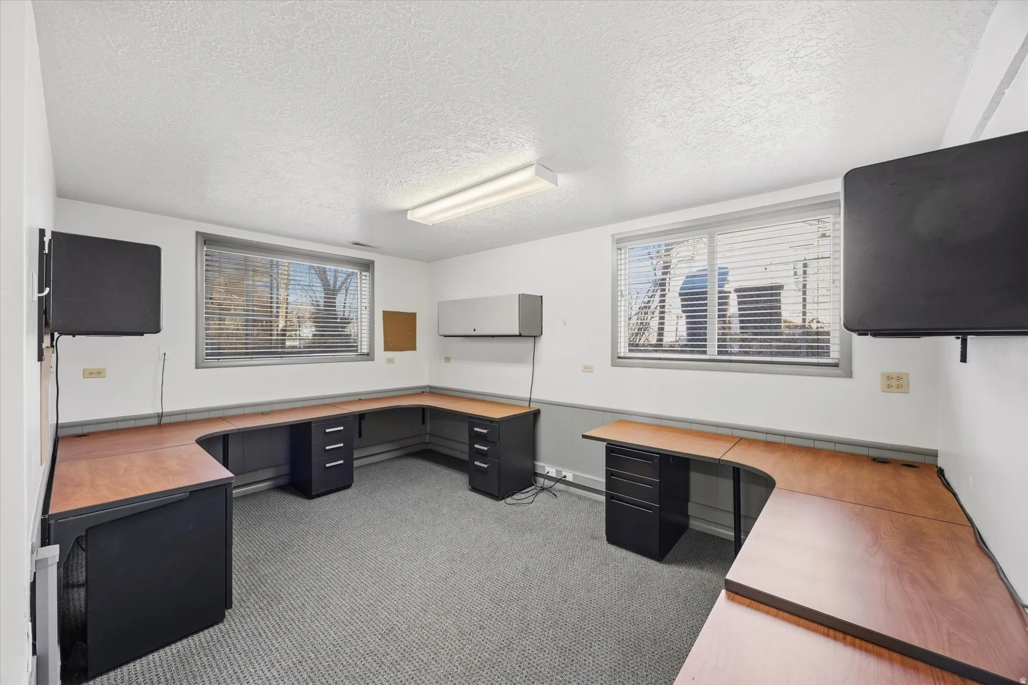 Unfurnished office with built in study area, light carpet, and a textured ceiling