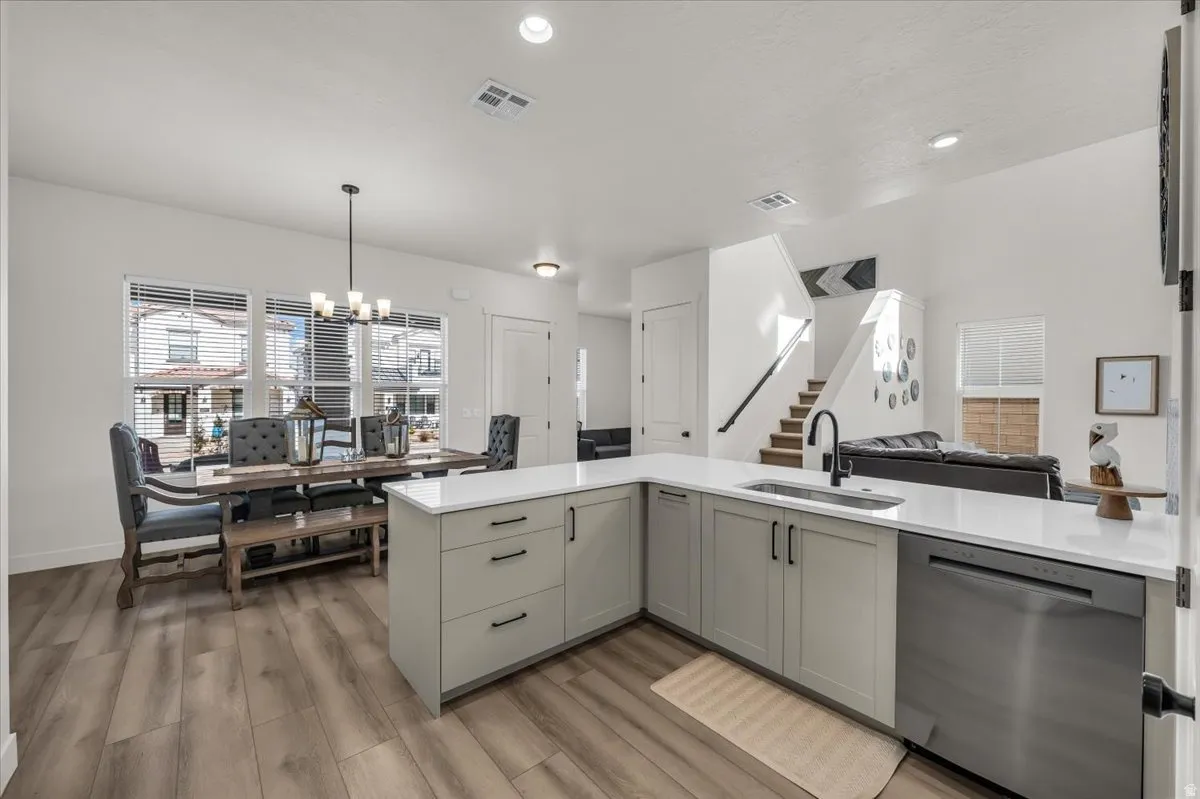 Kitchen featuring dishwasher, open floor plan, hanging lights, light wood-style floors, and gray cabinetry