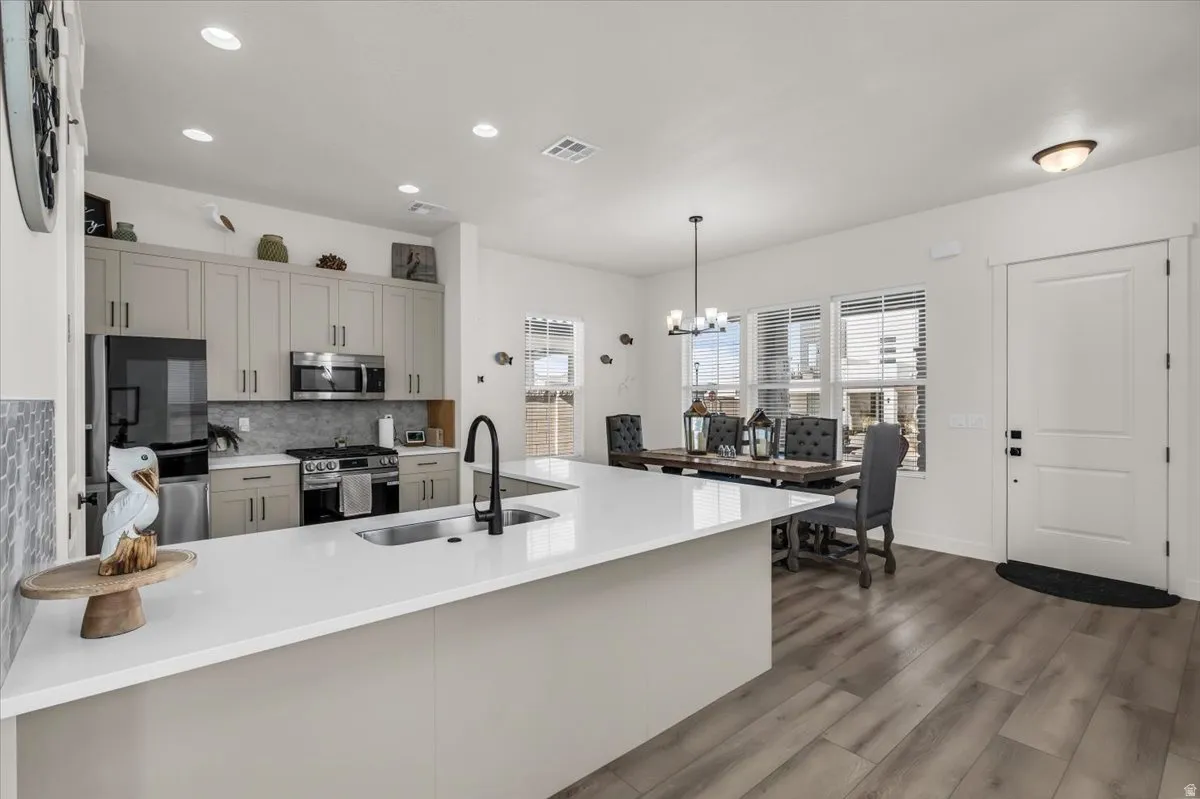 Kitchen featuring stainless steel appliances, dark wood finished floors, a peninsula, light stone countertops, and gray cabinetry