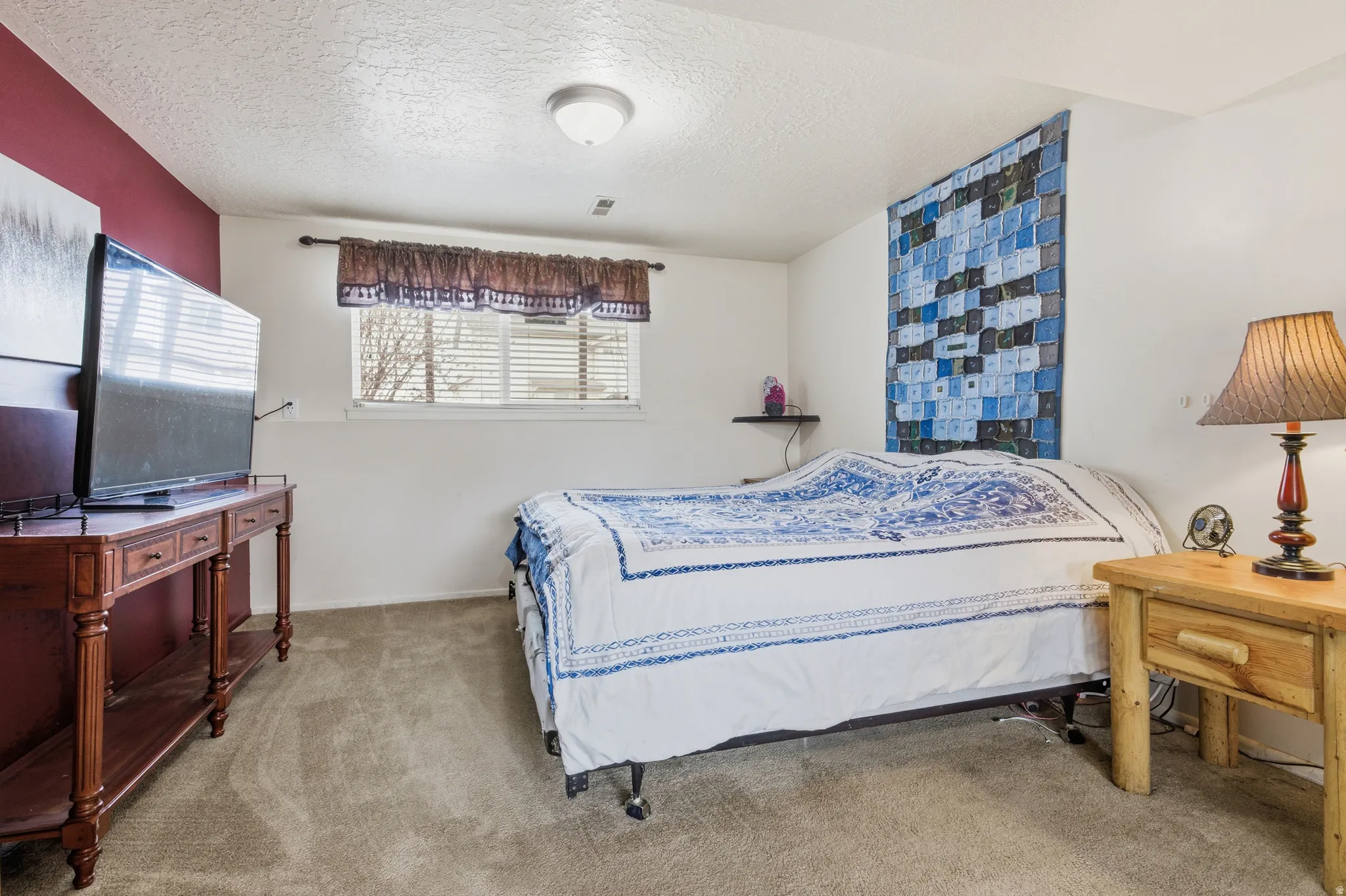 Carpeted bedroom with a textured ceiling and baseboards