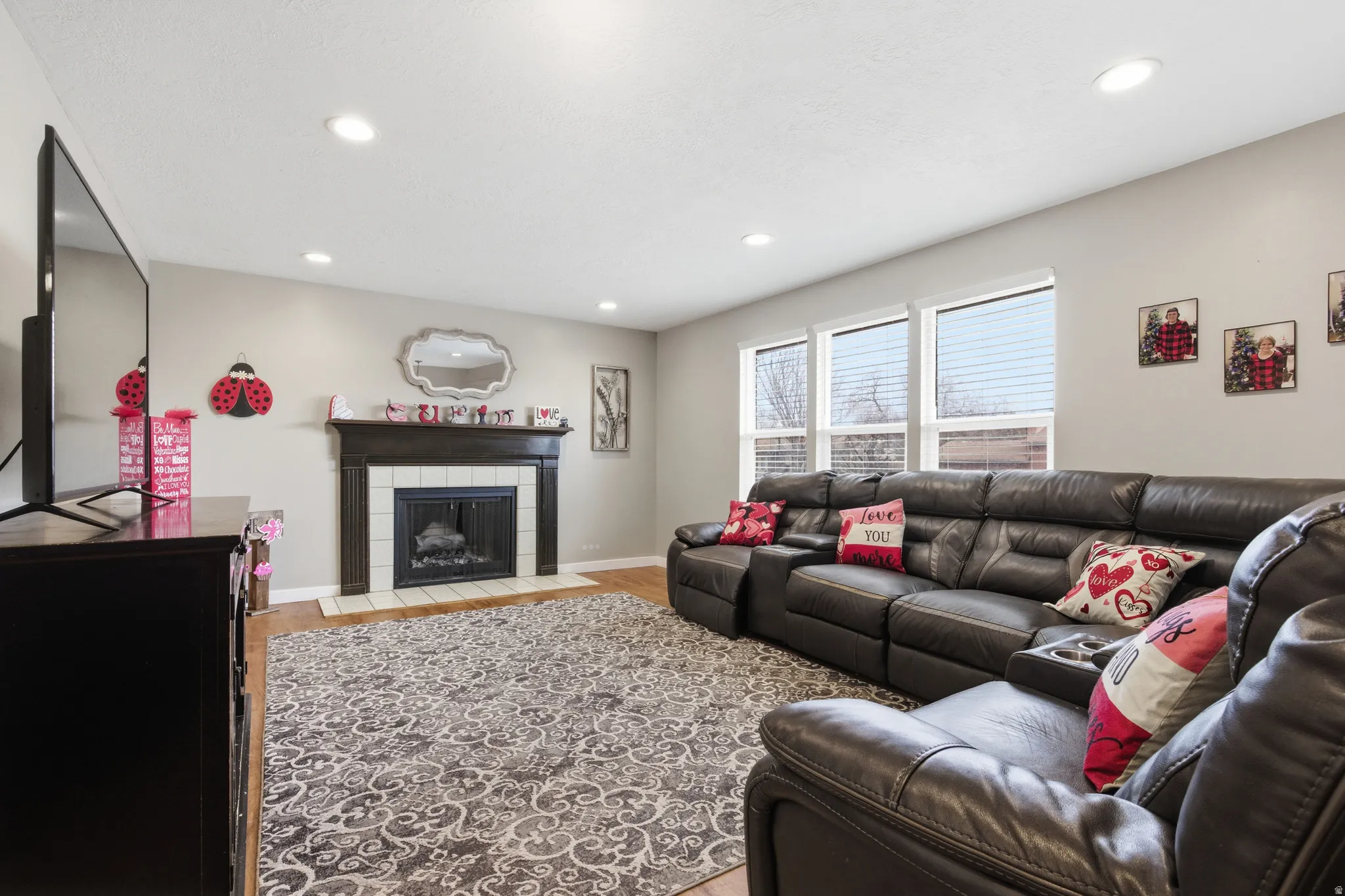 Living room with light wood finished floors, a tiled fireplace, and recessed lighting