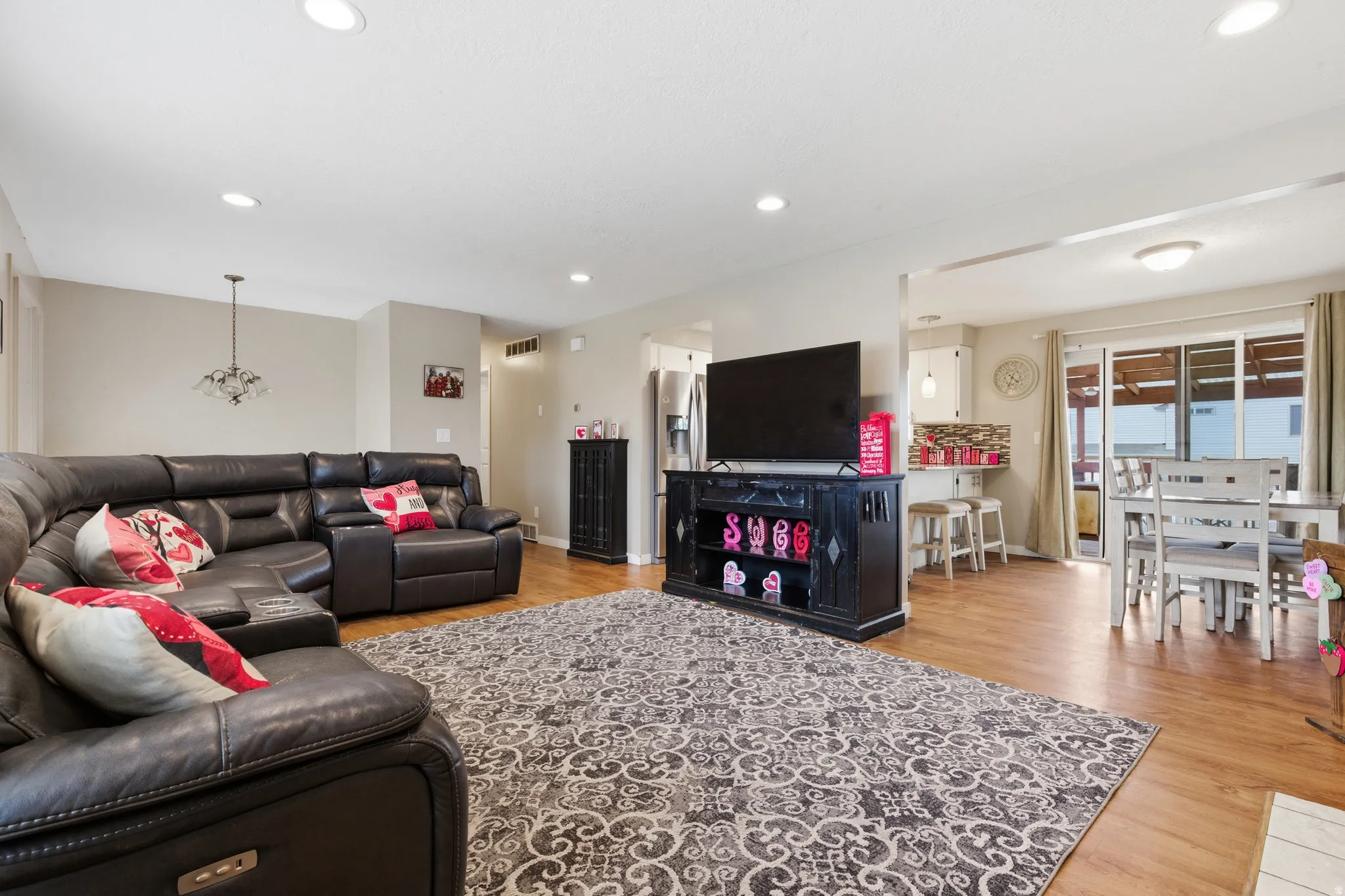 Living room with light wood-style flooring and suspended lighting