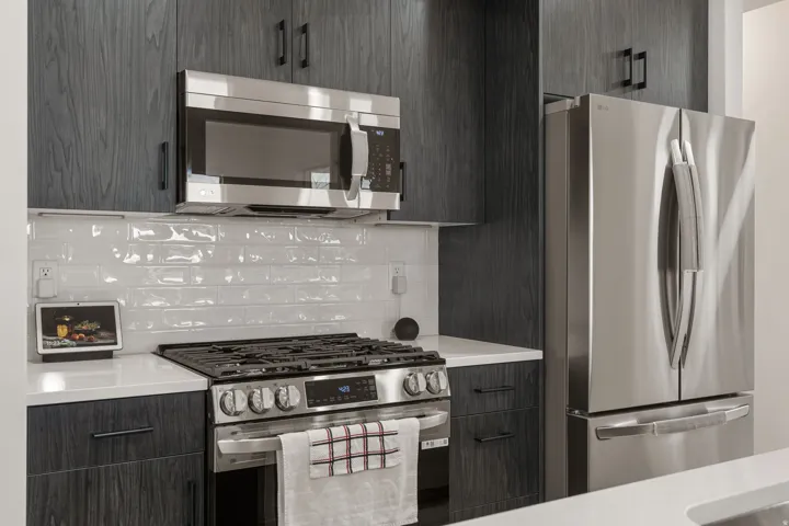 Kitchen featuring modern cabinets, stainless steel appliances, light stone countertops, and backsplash