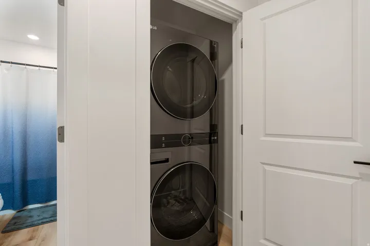 Laundry area featuring stacked washer and dryer and recessed lighting