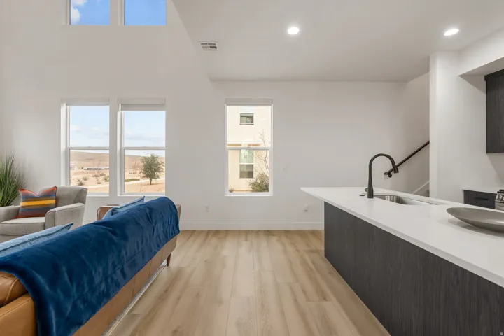 Living room featuring light wood-type flooring, healthy amount of natural light, recessed lighting, and a high ceiling