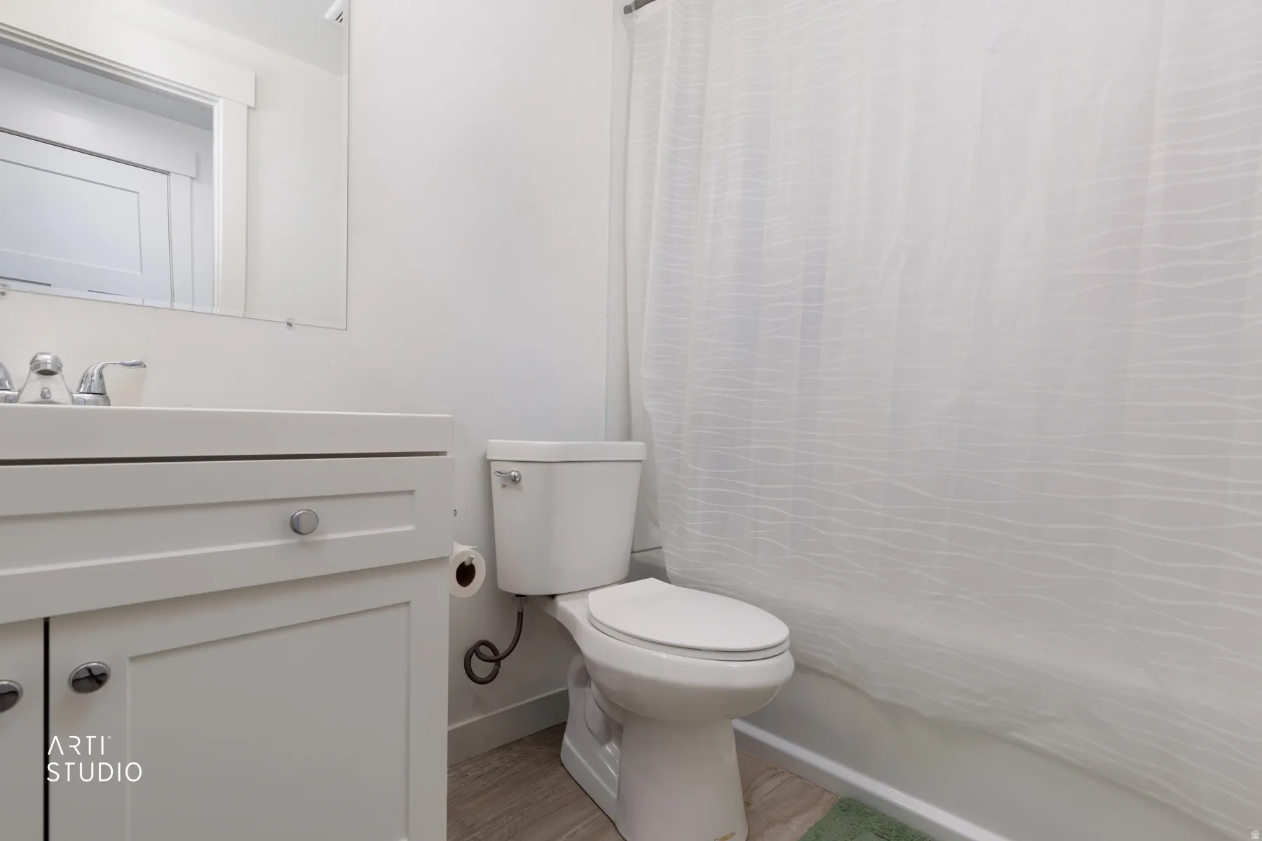Bathroom with vanity, shower / bath combo with shower curtain, and light wood finished floors
