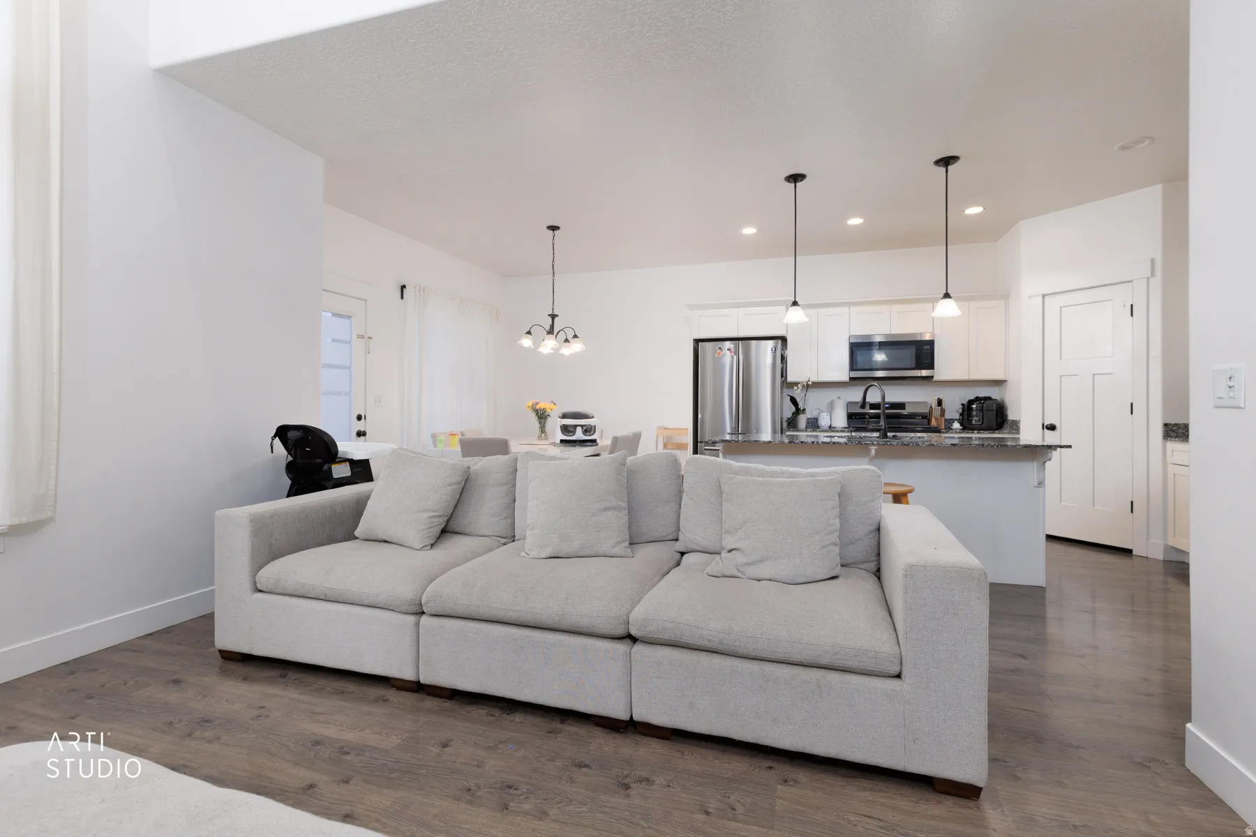 Living area featuring hanging lights and dark wood-style floors