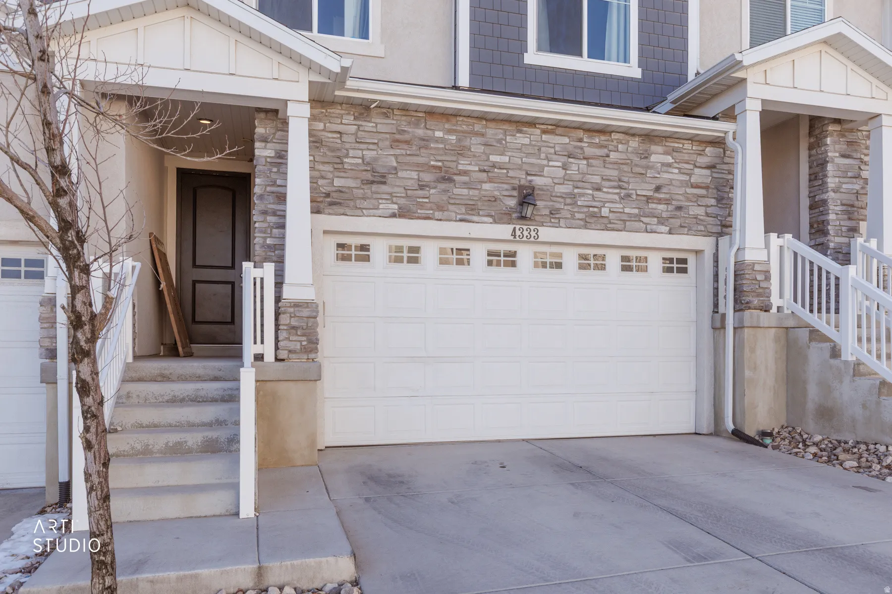 Doorway to property featuring stone siding, driveway, and an attached garage