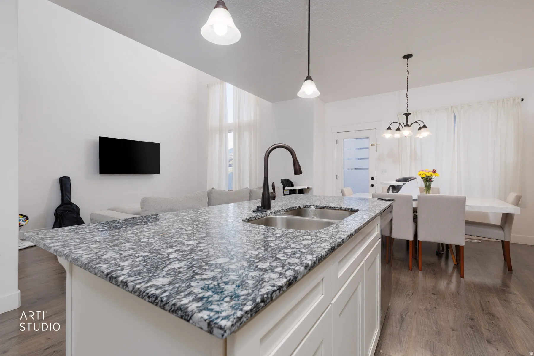Kitchen featuring light stone counters, dark wood-style floors, a center island with sink, and white cabinets