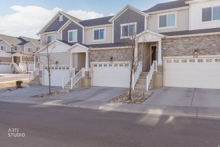 View of front of property with stone siding, concrete driveway, an attached garage, and board and batten siding