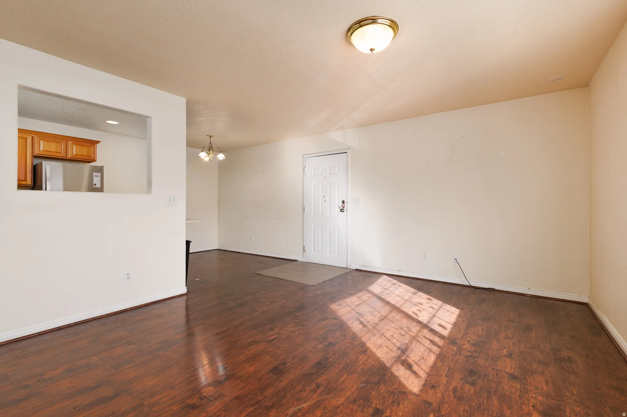 Empty room with a chandelier and dark wood-style flooring