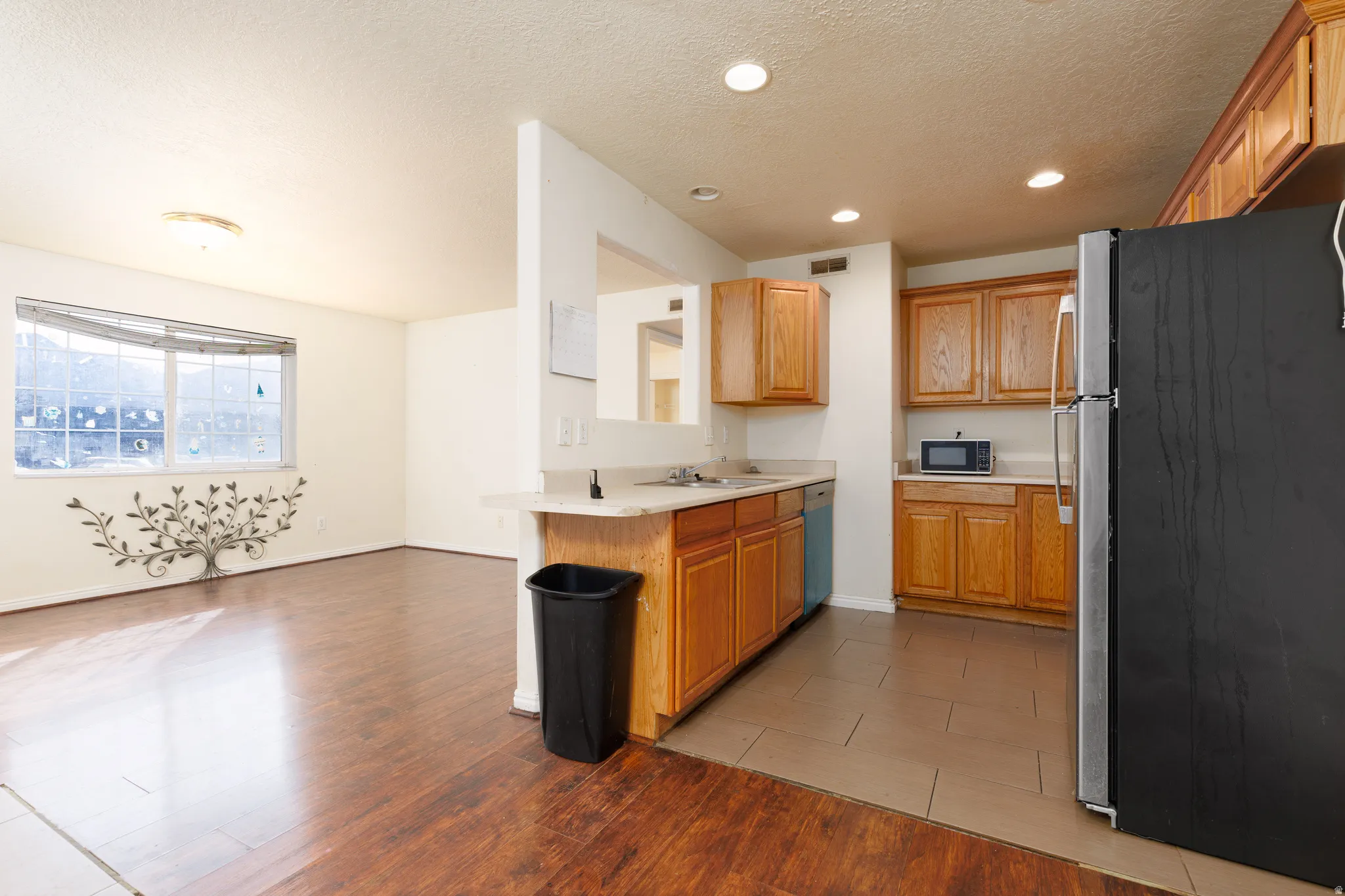 Kitchen with stainless steel appliances, light countertops, a textured ceiling, light wood-style flooring, and wood finish cabinets