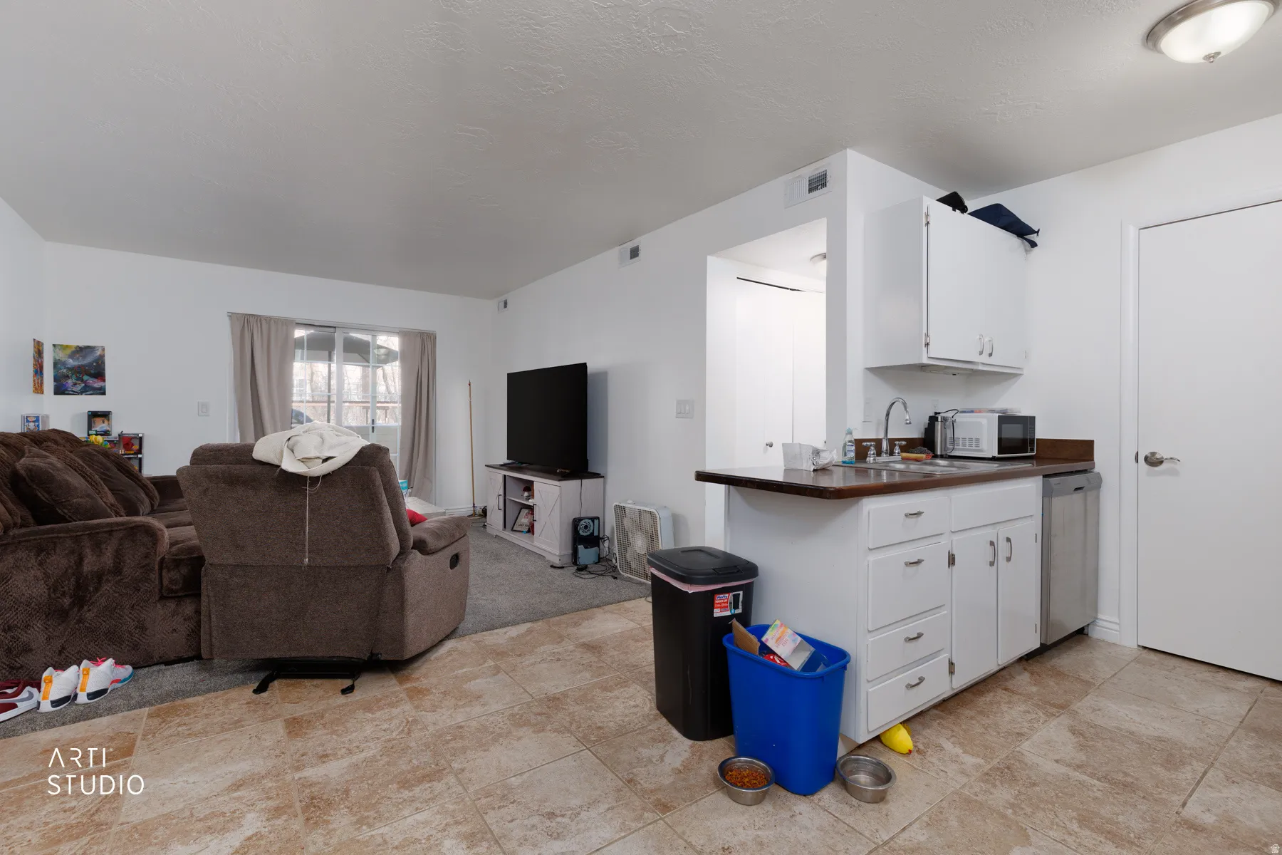 Kitchen featuring white cabinets, open floor plan, dark countertops, stainless steel appliances, and a peninsula