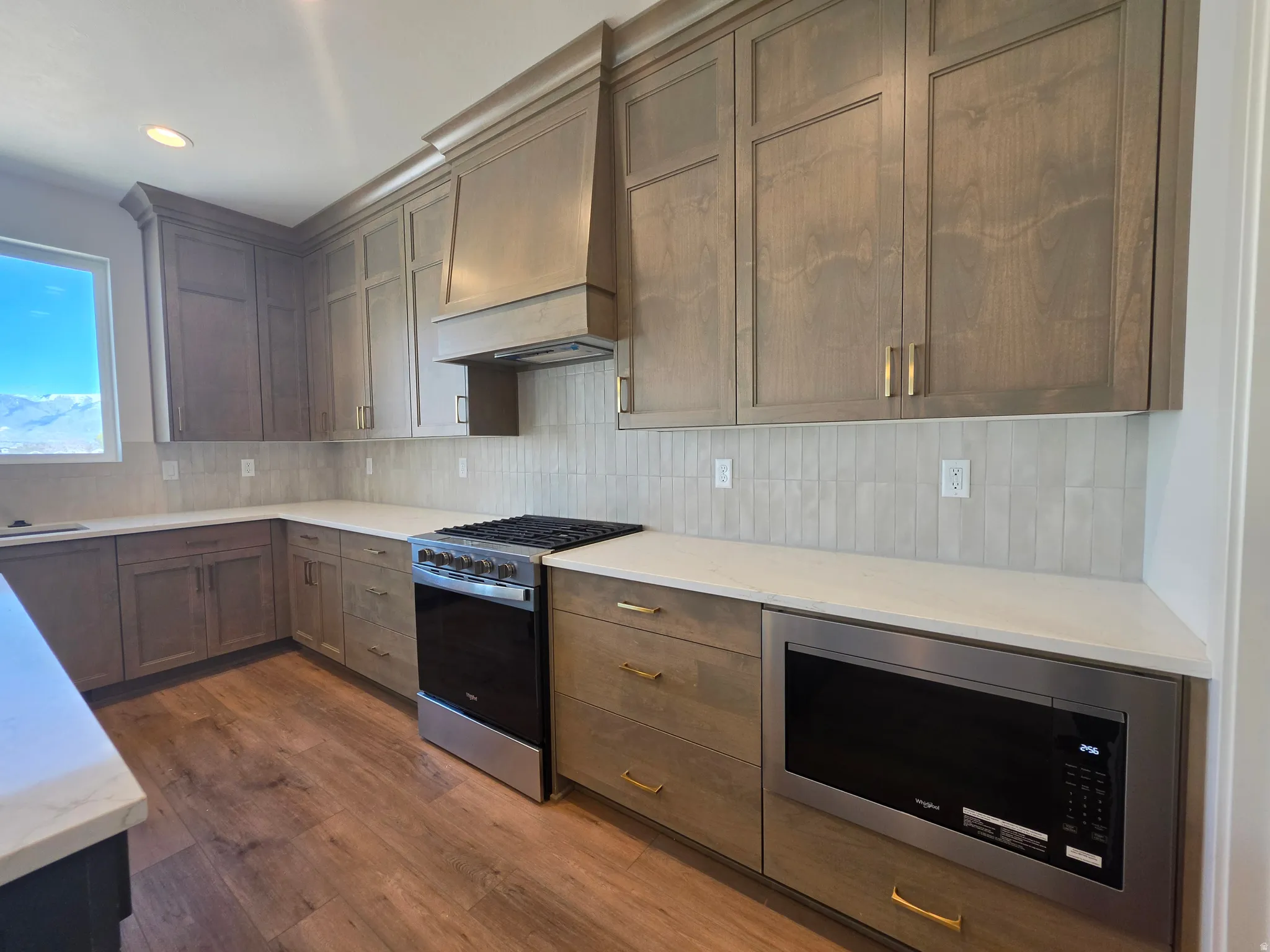 Kitchen with stainless steel appliances, backsplash, dark wood finished floors, light stone countertops, and recessed lighting