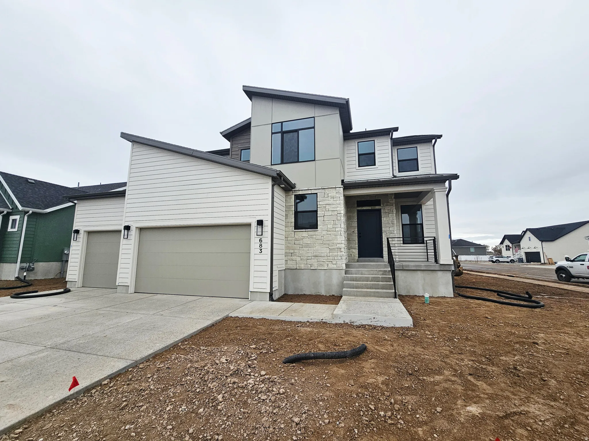 Contemporary house with stone siding, driveway, an attached garage, and a porch