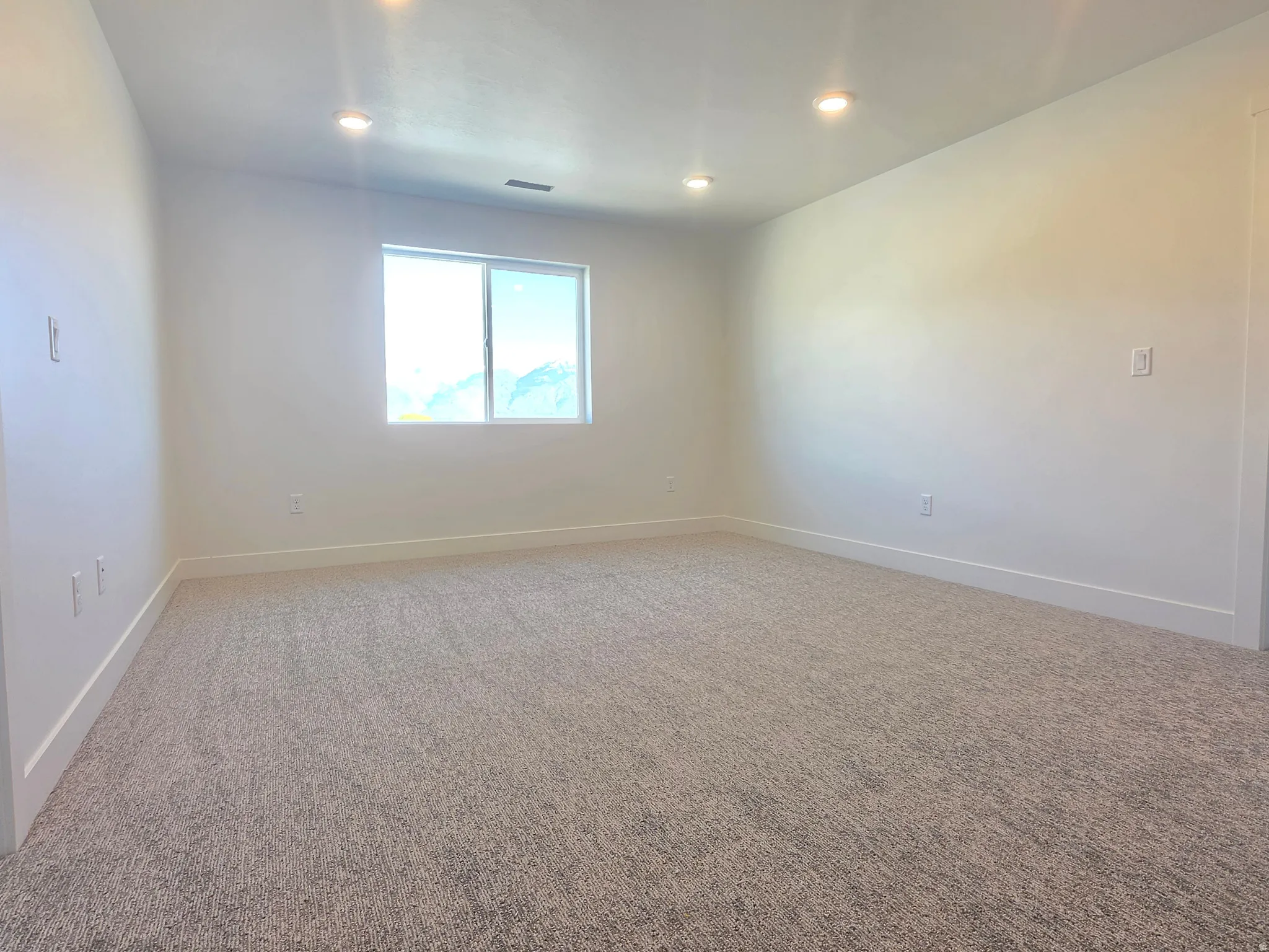 Carpeted spare room with baseboards and recessed lighting