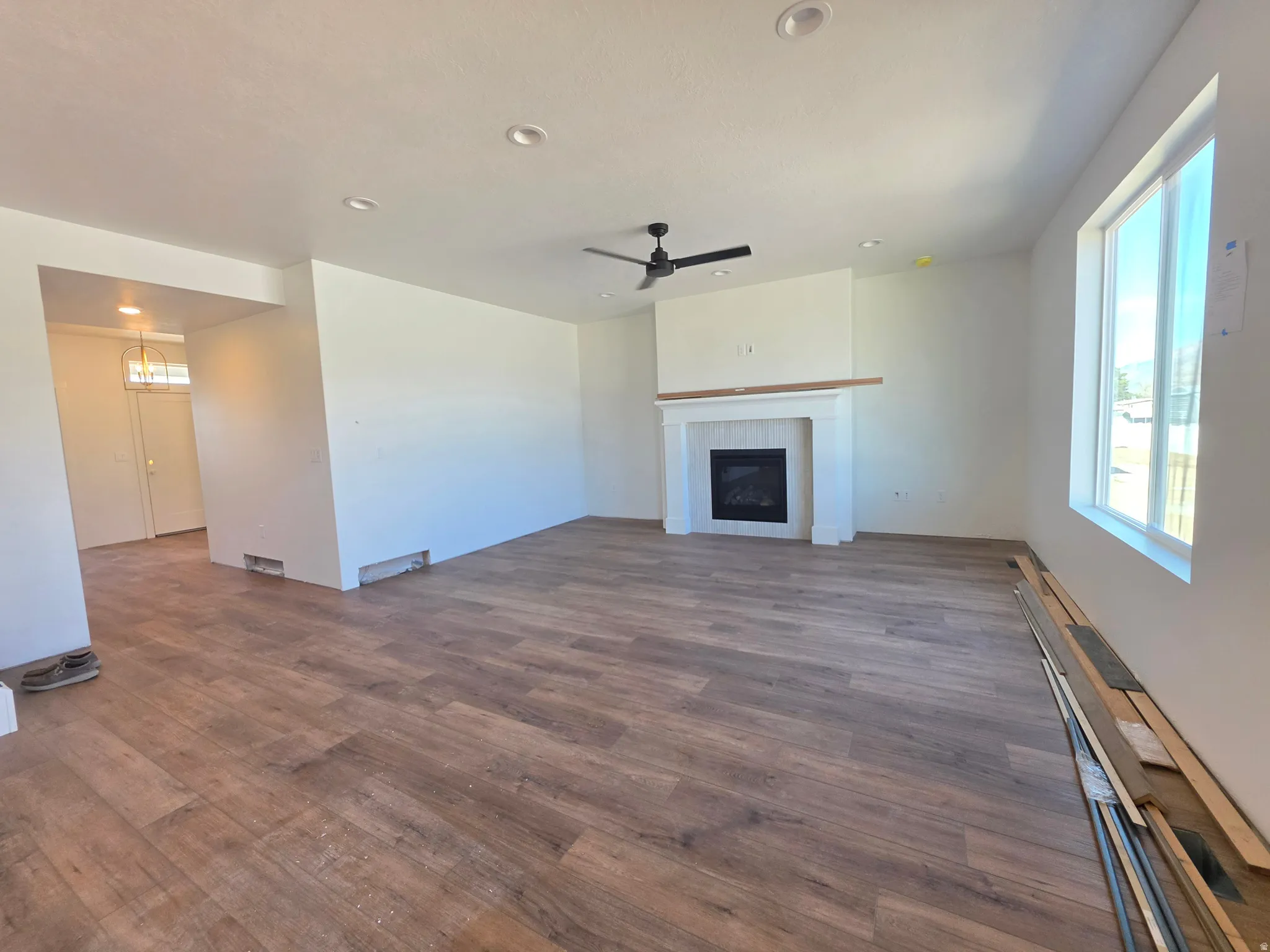 Unfurnished living room with dark wood-type flooring, ceiling fan, a tile fireplace, and recessed lighting