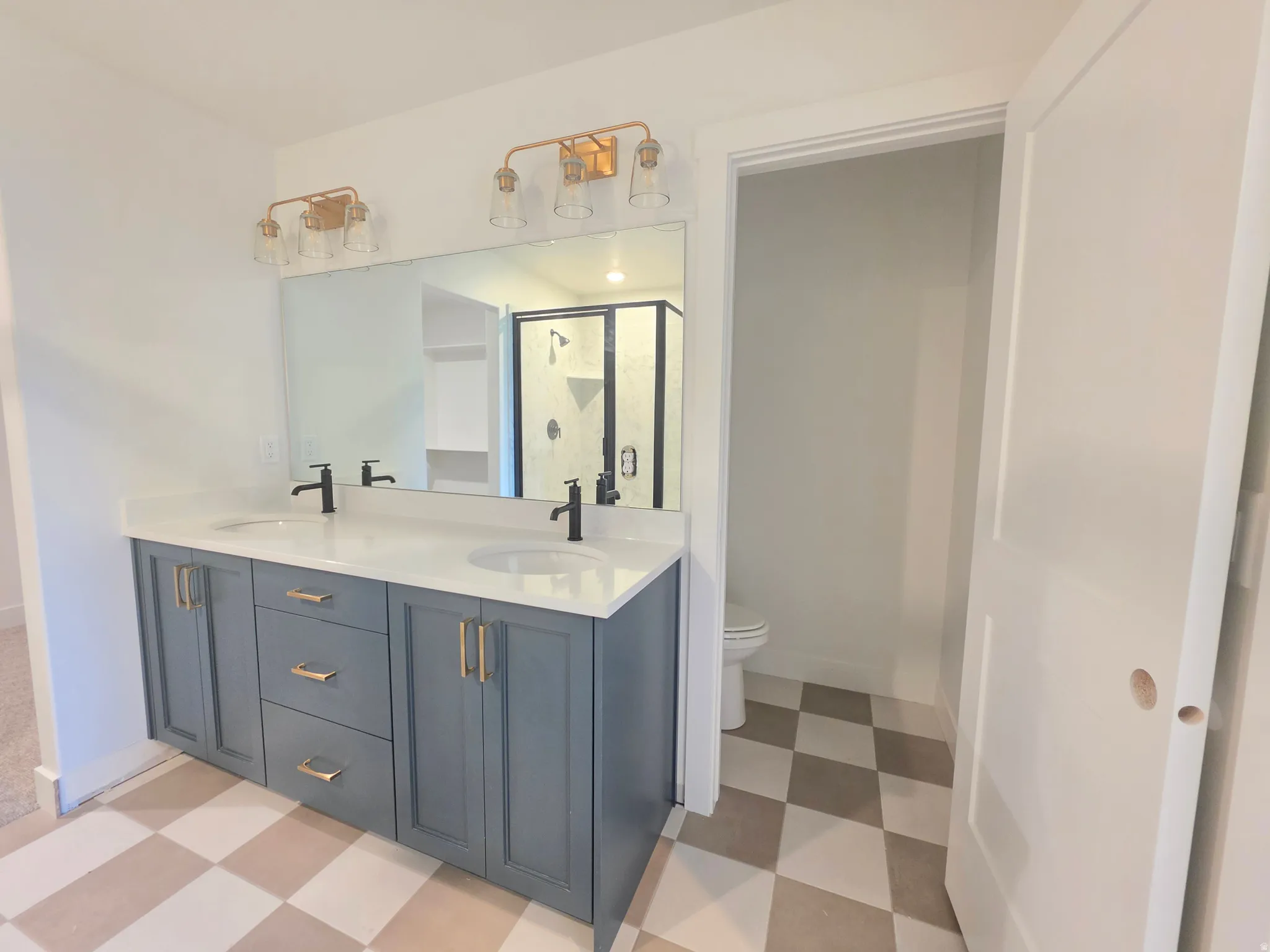 Bathroom with light flooring, double vanity, and a stall shower