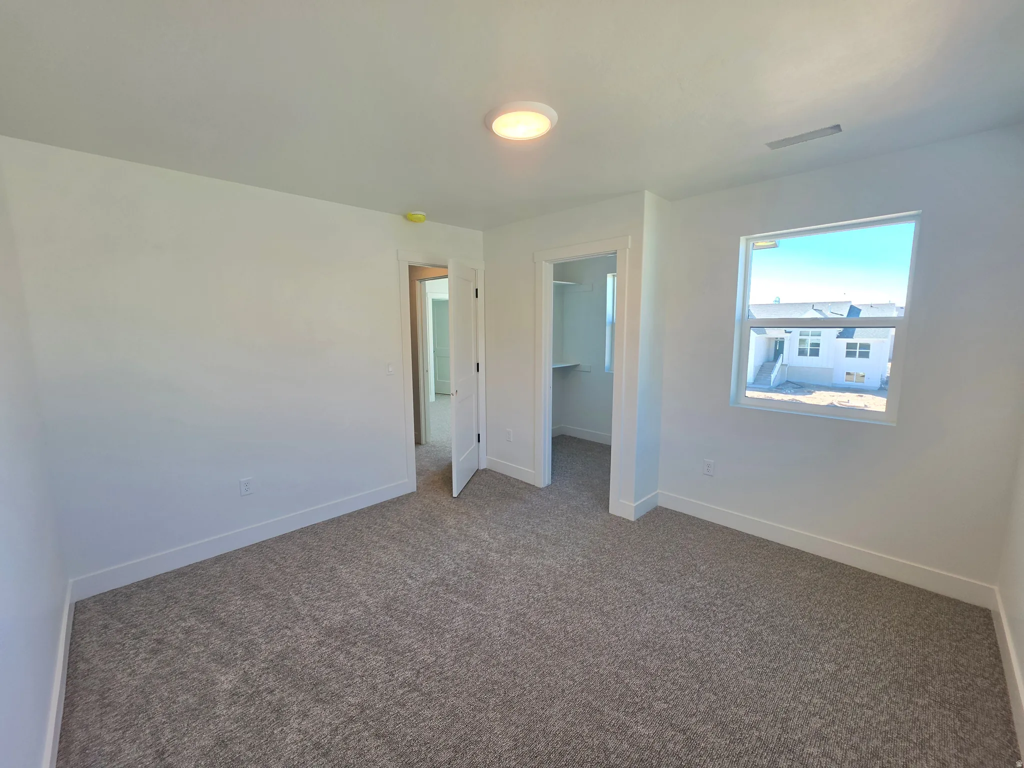 Unfurnished bedroom featuring a walk in closet and dark carpet