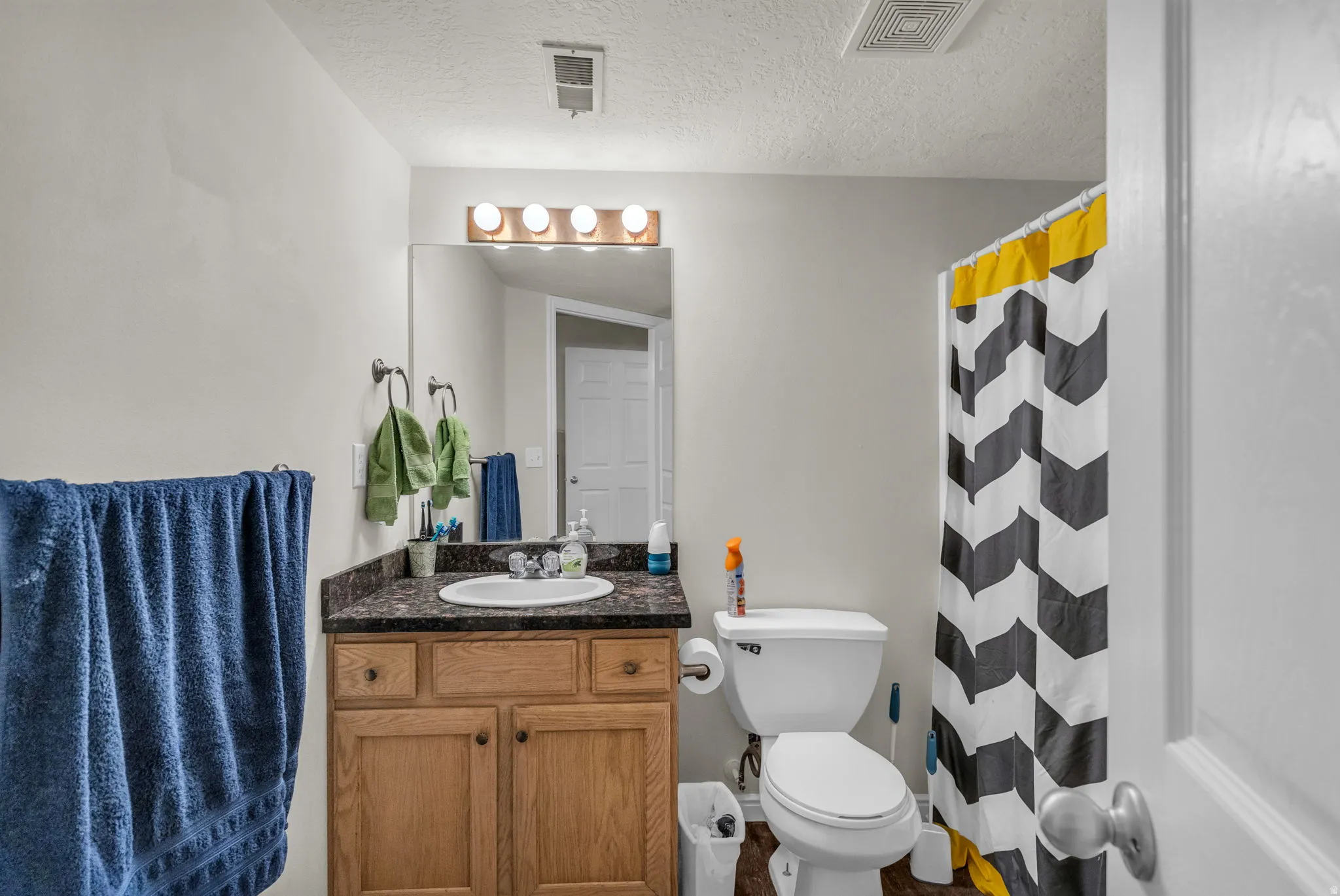 Full bath with a shower with curtain, vanity, and a textured ceiling