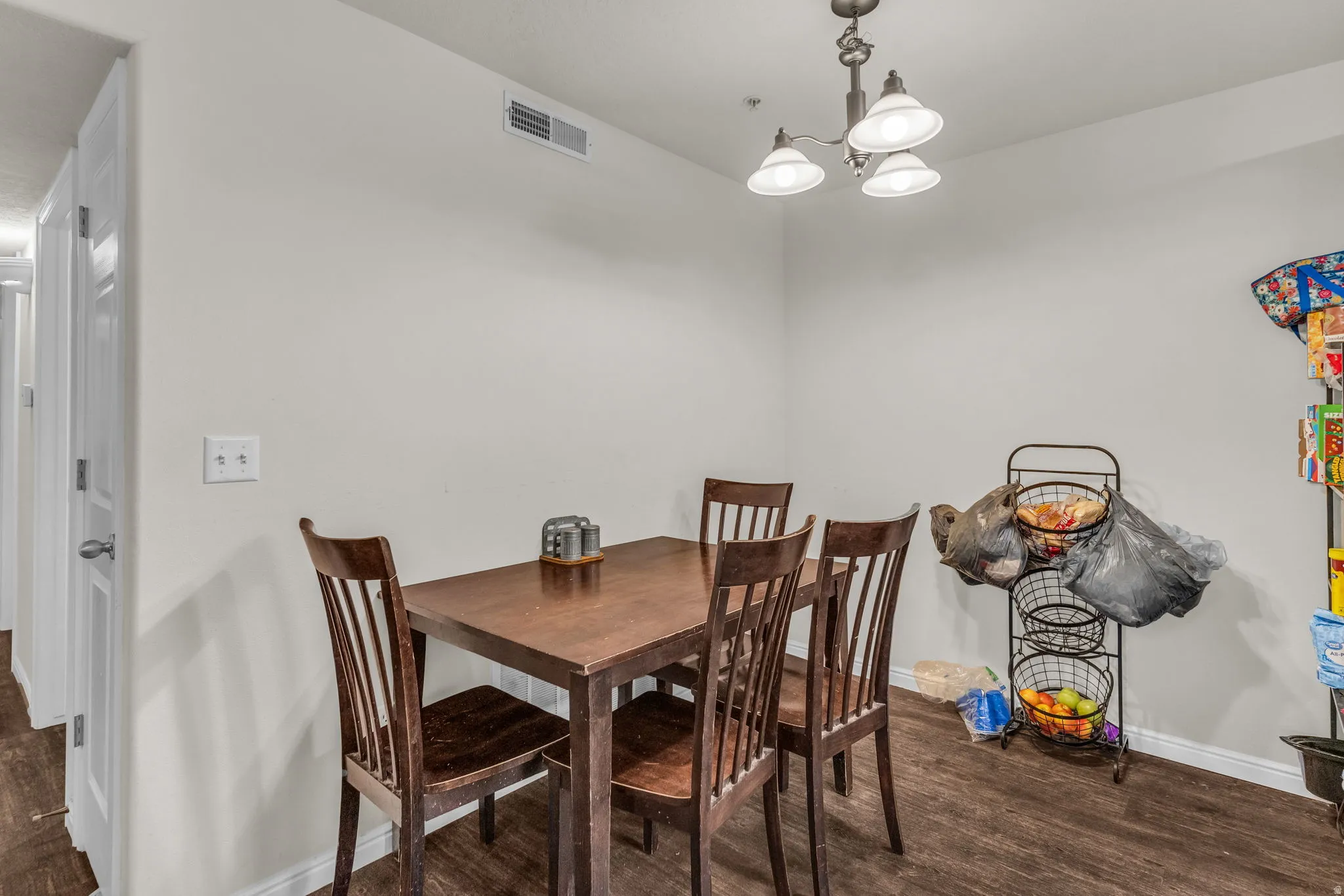 Dining area with a chandelier and dark wood-type flooring