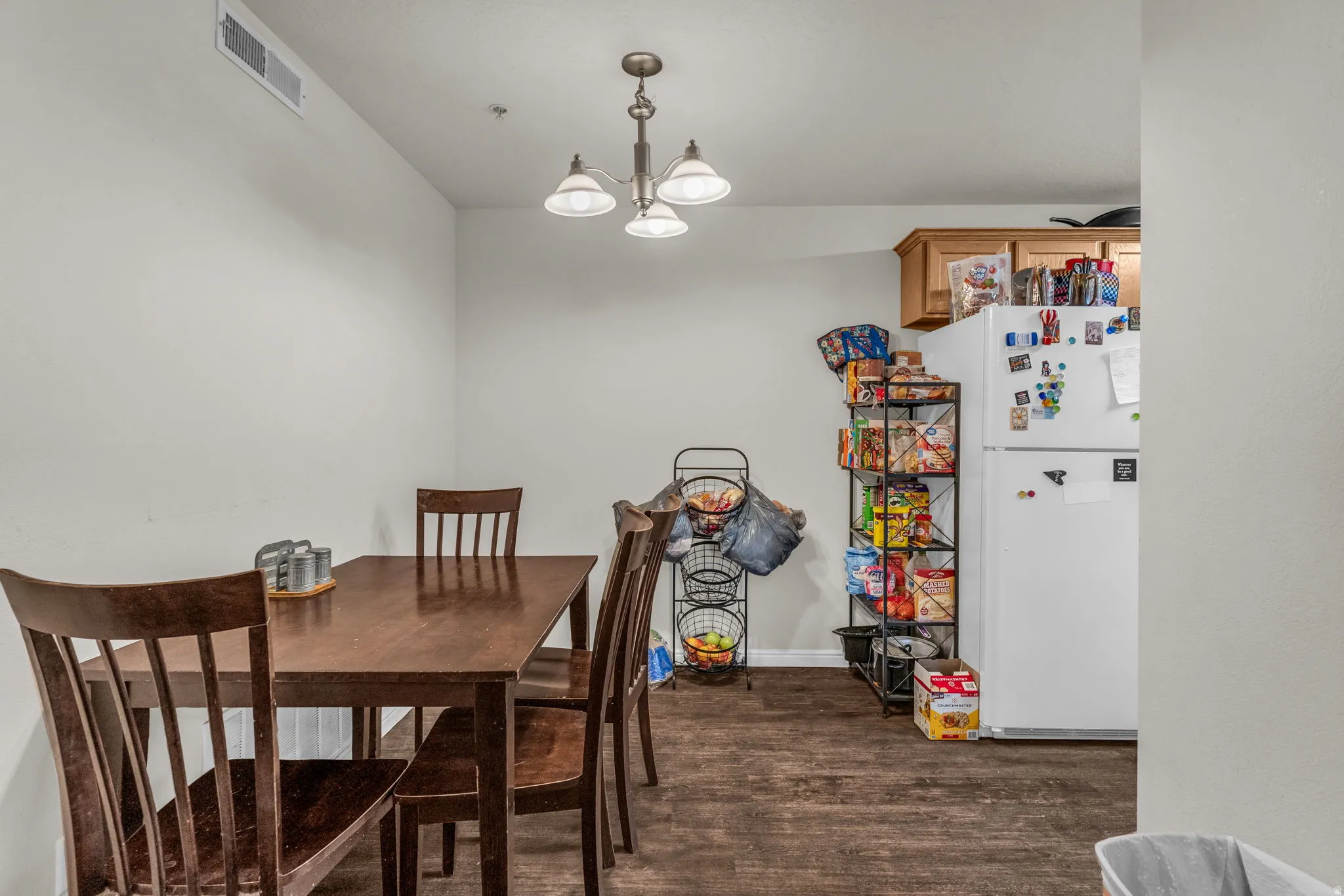 Dining space featuring dark wood-type flooring and suspended lighting