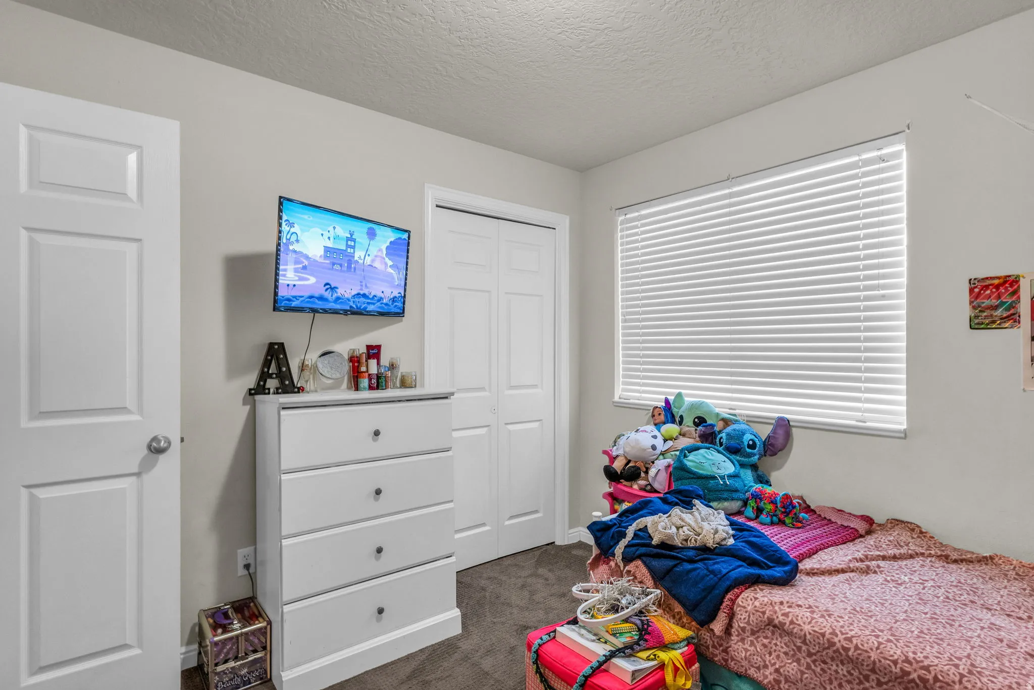 Bedroom featuring dark carpet, a textured ceiling, and a closet