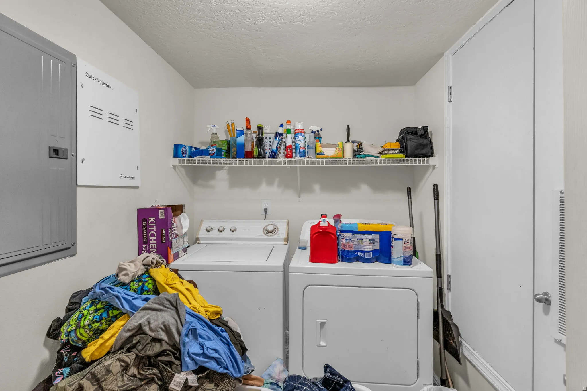 Laundry room featuring electric panel, independent washer and dryer, and a textured ceiling