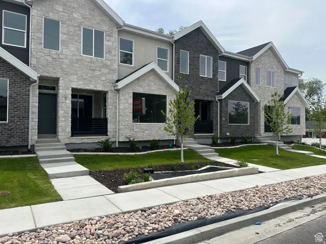 Modern townhome exterior with mixed material facade, featuring light-colored stone and dark brick