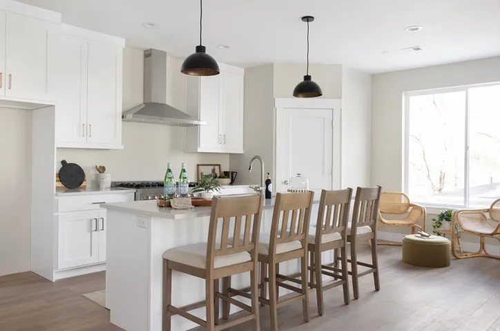 Kitchen with a breakfast bar, wood finished floors, a kitchen island with sink, white cabinetry, and pendant lighting