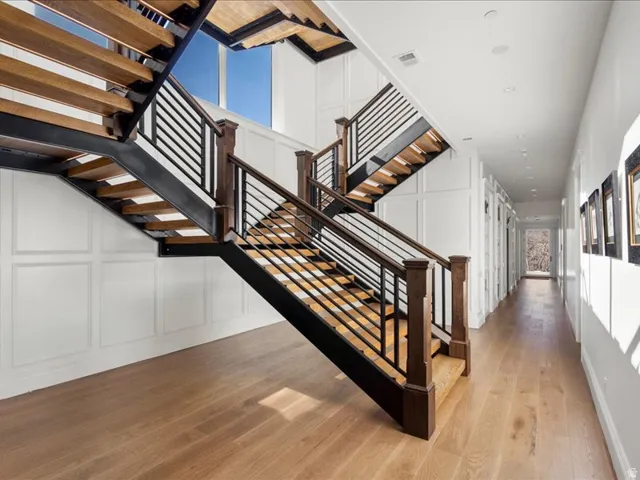 Staircase with a decorative wall and hardwood / wood-style floors