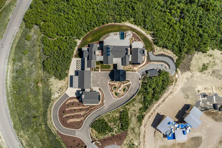 Expansive property featuring a multi-structure residence with dark-toned roofing, a swimming pool, and extensive paved driveways