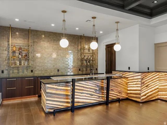 Bar area featuring modern cabinets, pendant lighting, dark wood finish cabinetry, and dark stone countertops