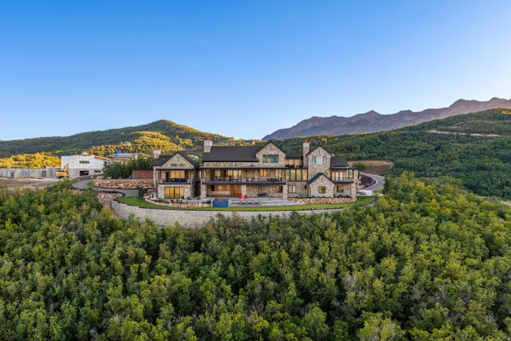 Stone exterior residence featuring multiple balconies, extensive window systems, and a multi-level roofline